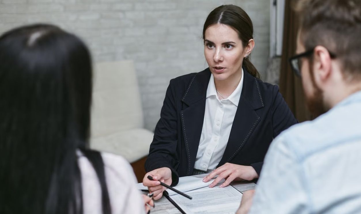 Three colleagues engaged in a business meeting discussing documents at a table indoors