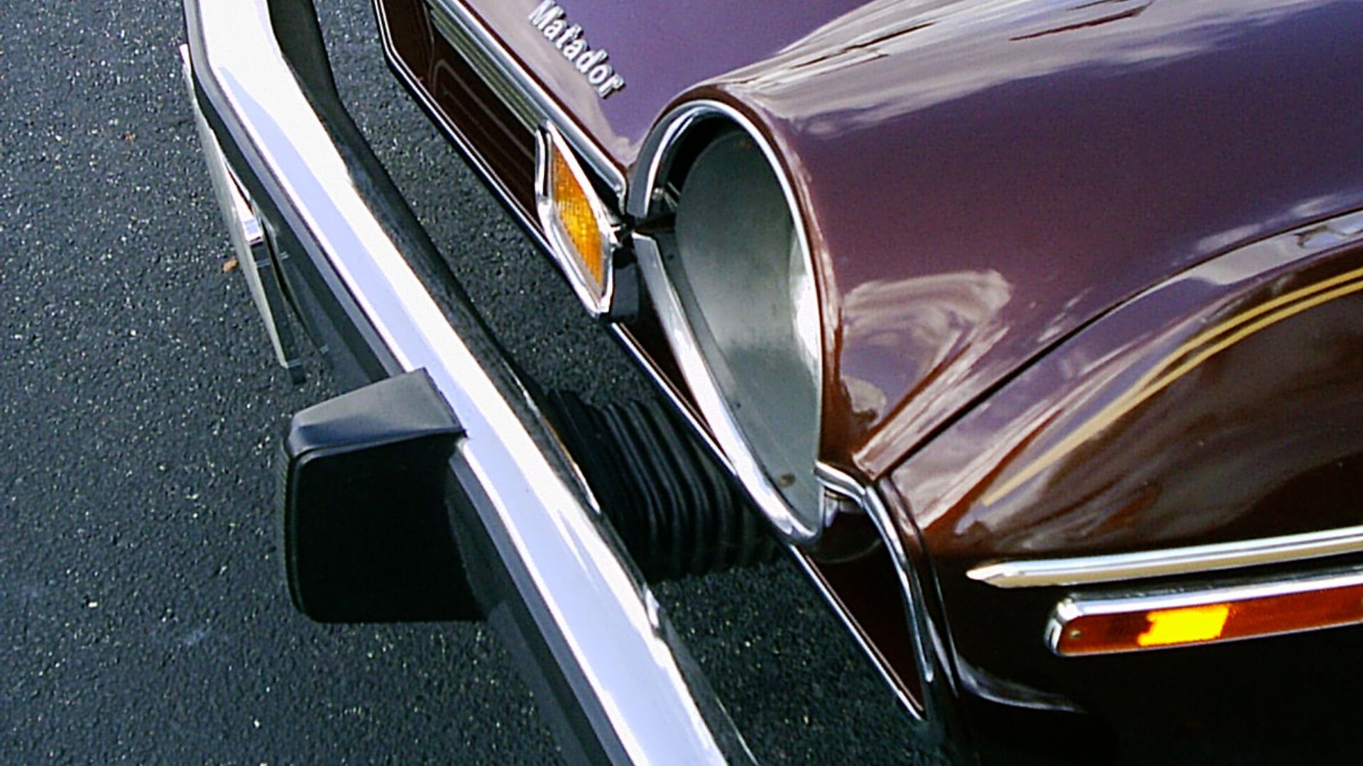 1976 AMC Matador Coupe - Brougham edition finished in Dark Cocoa Metallic (paint code: H4) with optional vinyl roof cover. Detail of energy absorbing front bumper designed to withstand the U.S. government standard for 5-mile-per-hour (8 km/h) impact witho