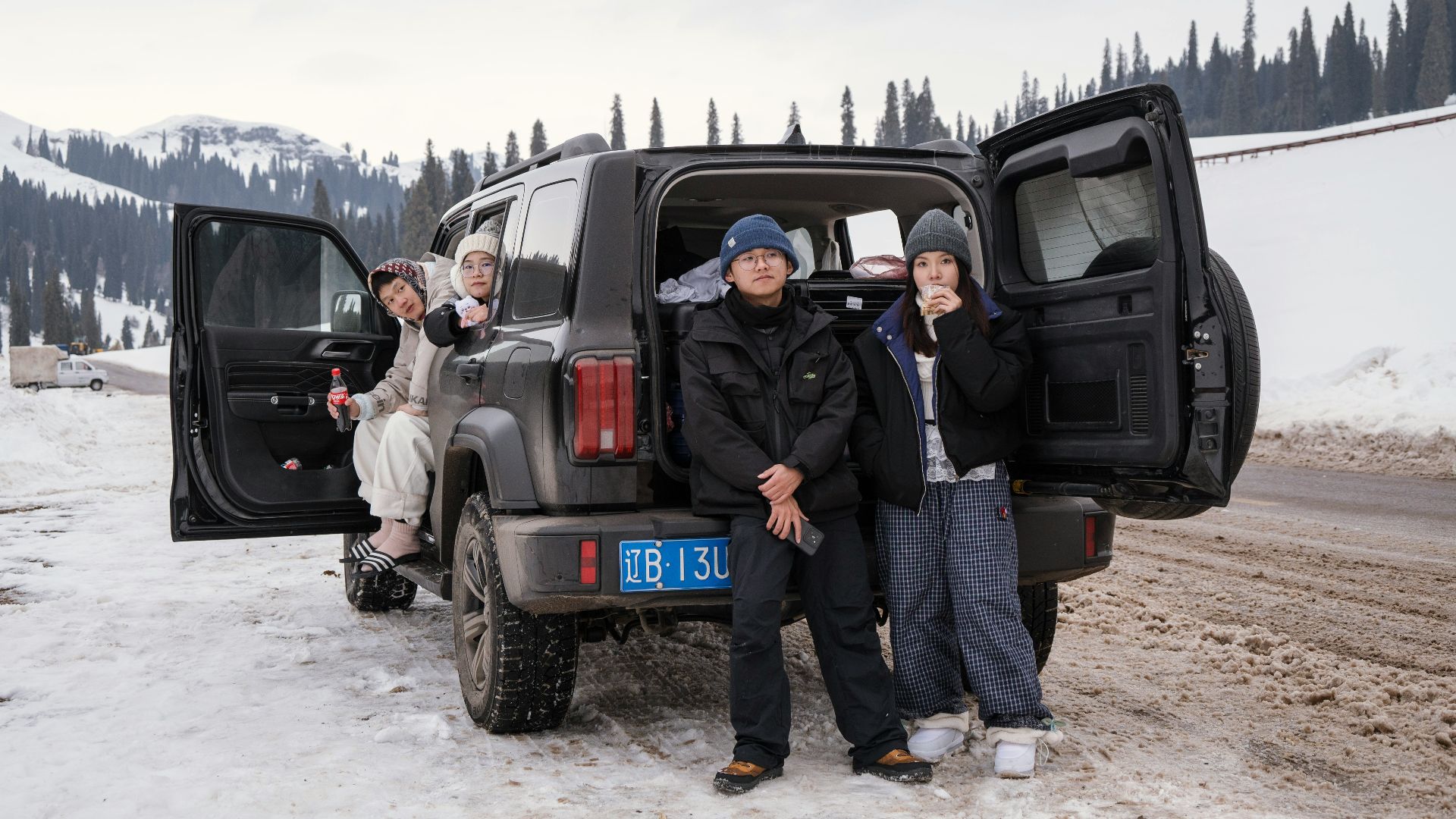 People gathered around a car in a snowy landscape.