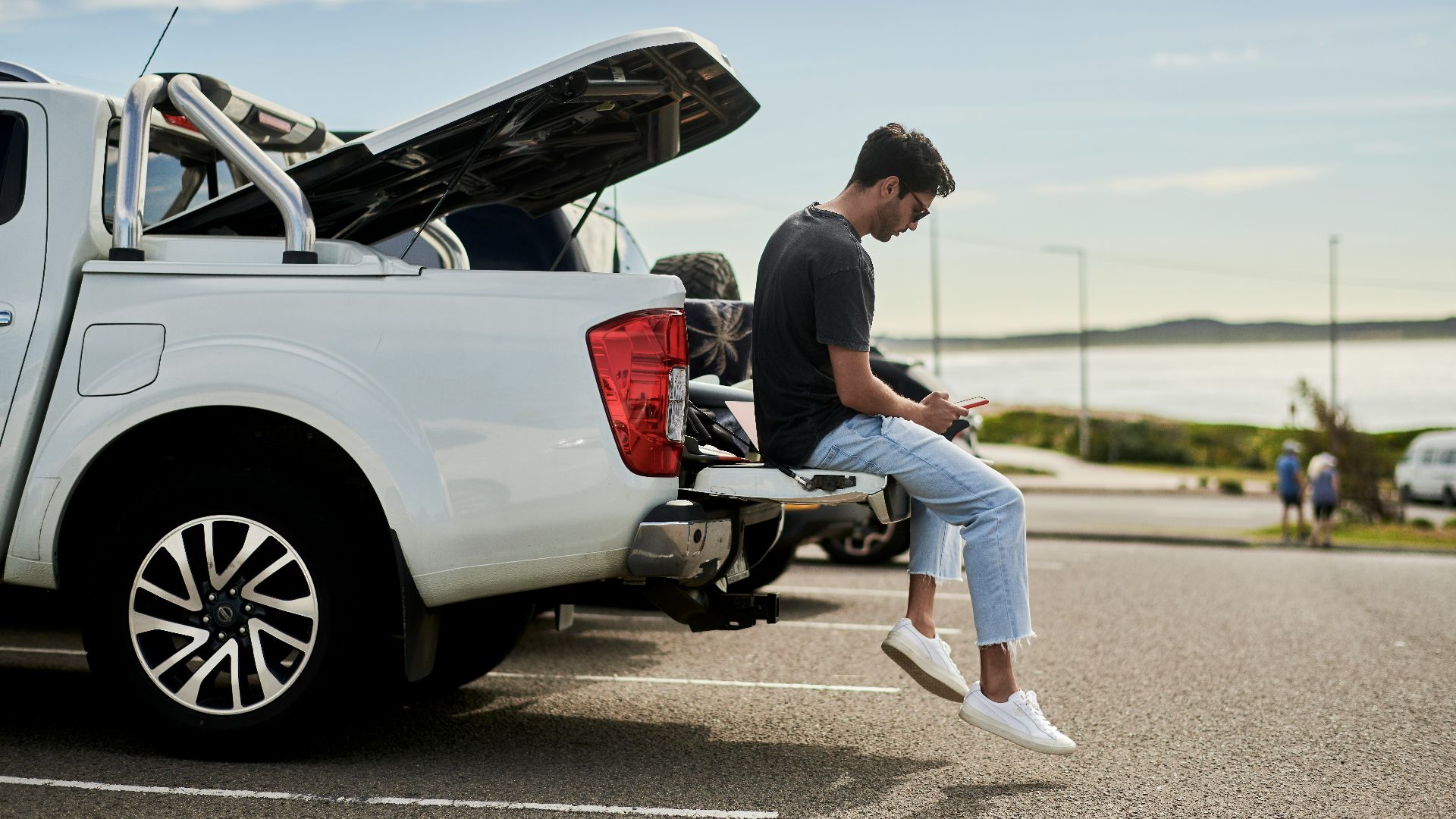 man sitting on car looking at phone