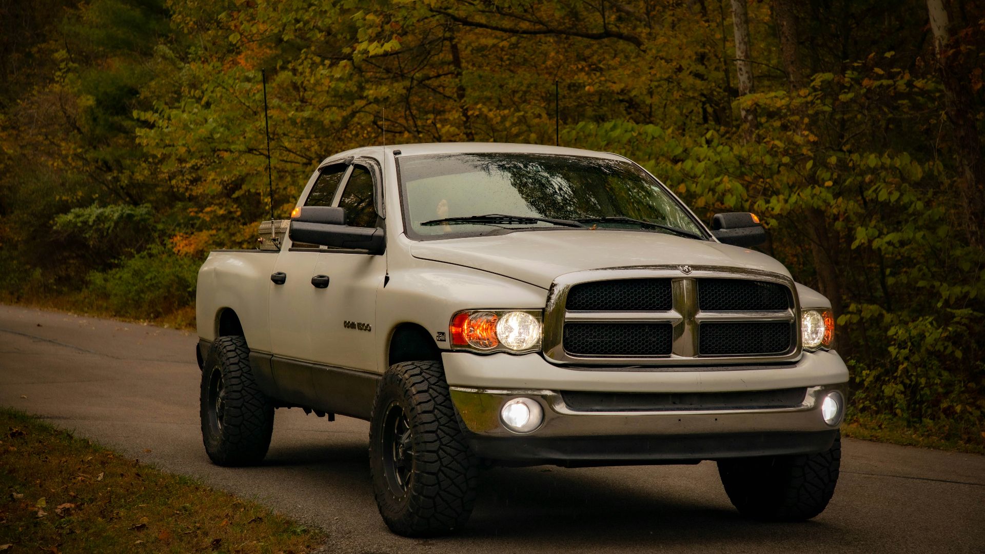 White pickup truck driving on a road.