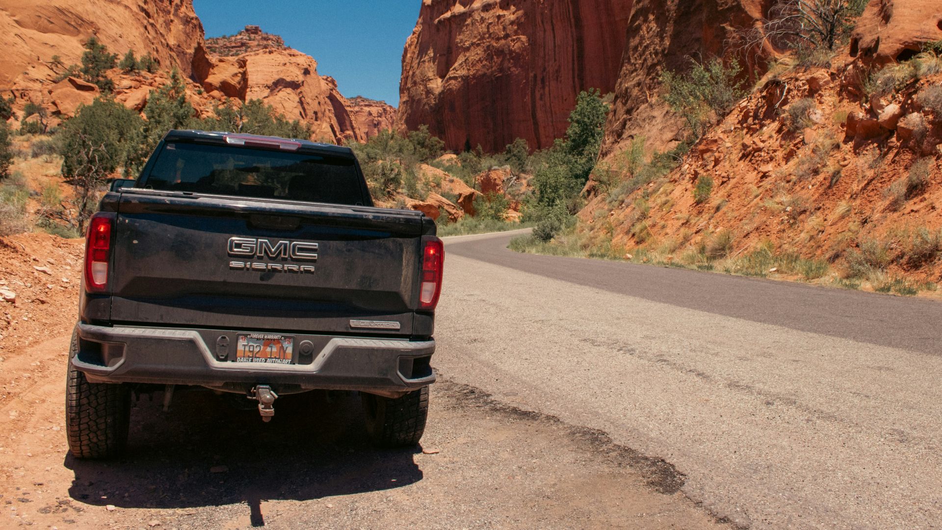 A black truck driving down a desert road