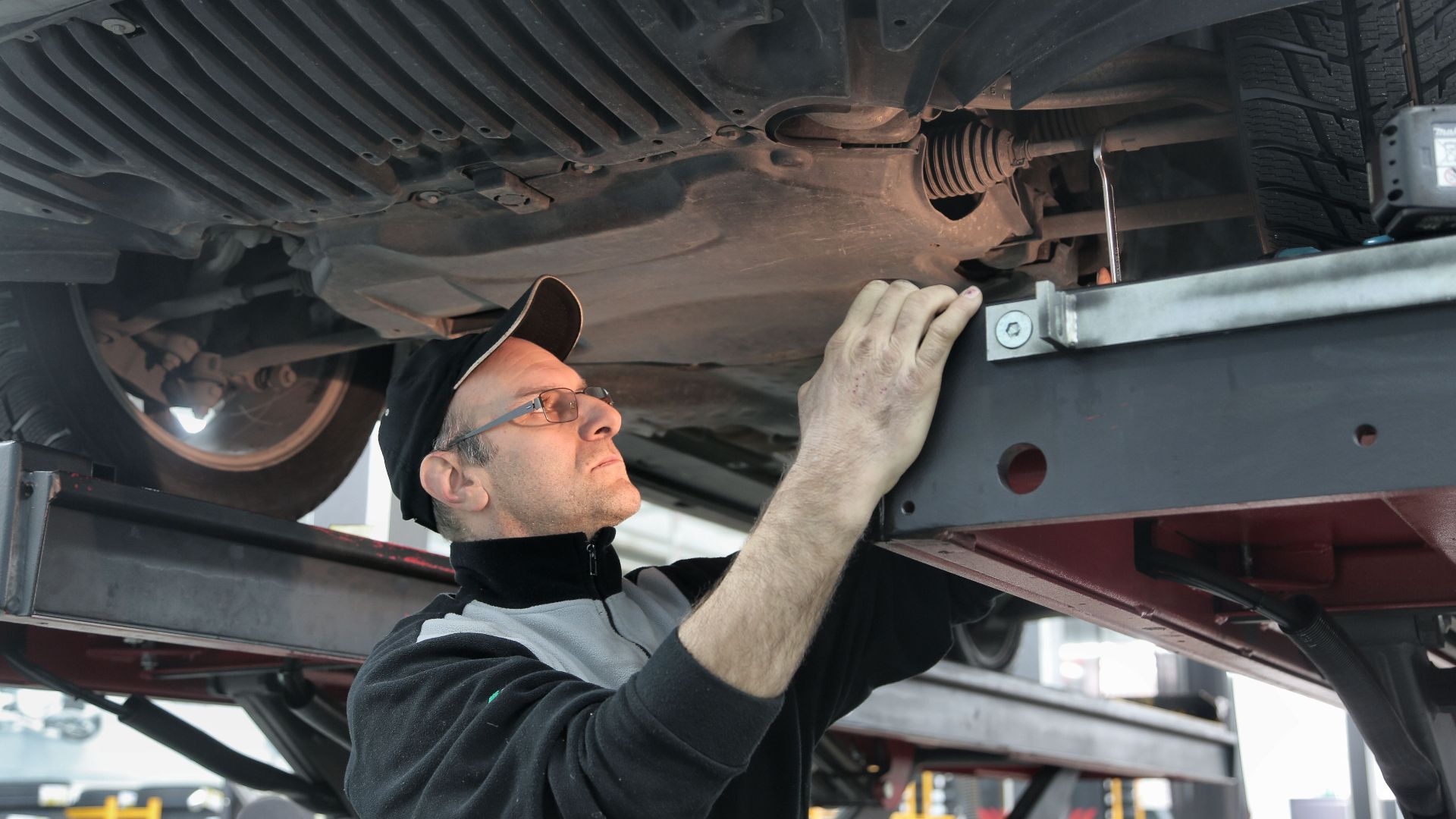 Professional mechanic conducting vehicle inspection in an auto workshop.