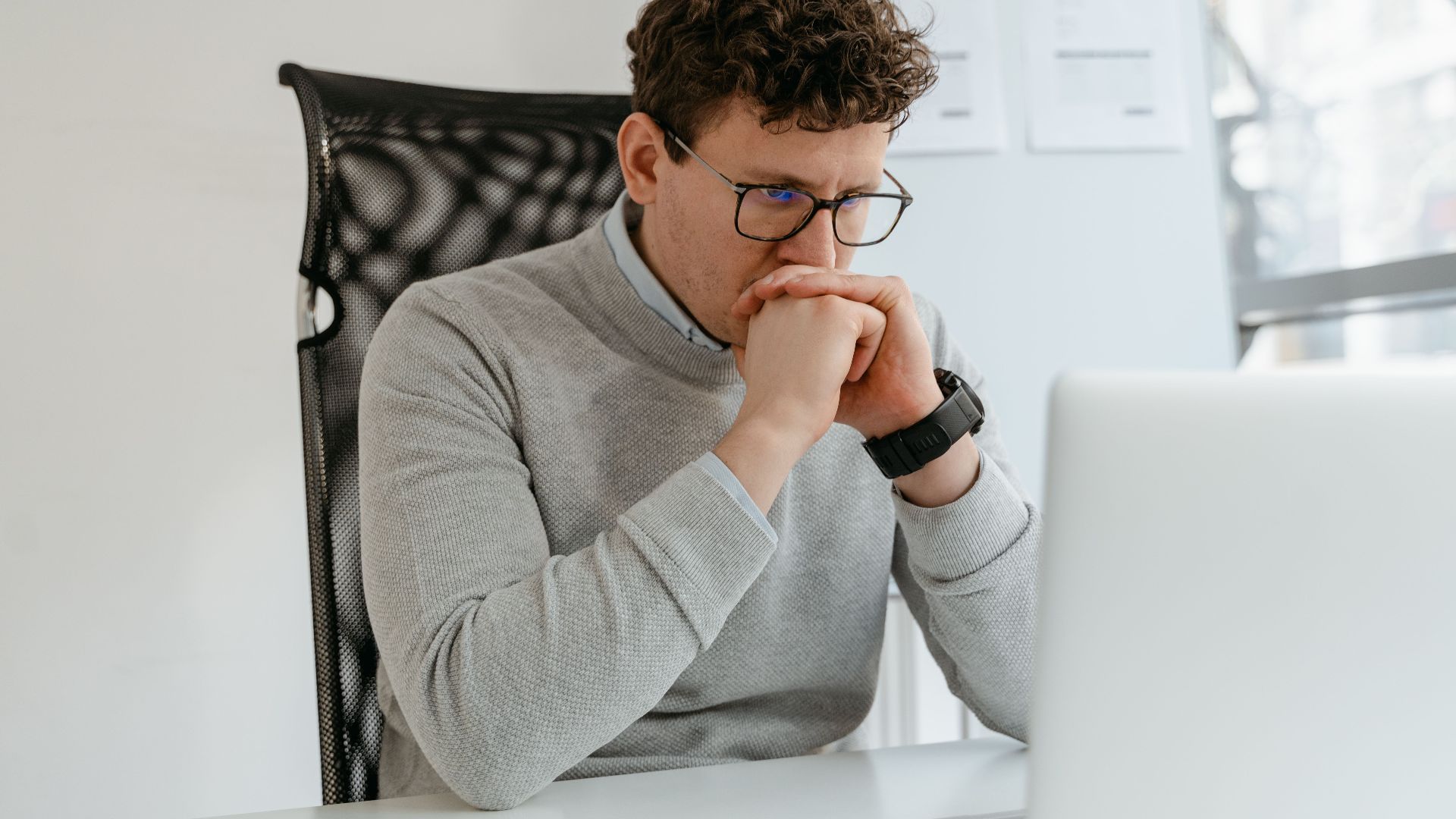A thoughtful businessman wearing glasses, engaged in work at the office.