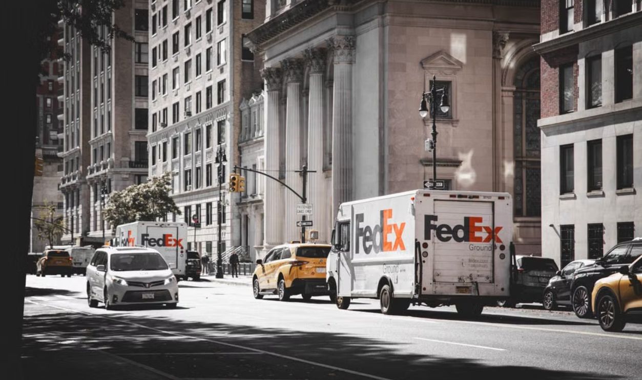 Busy street in New York City with delivery vans and cars in front of historic architecture