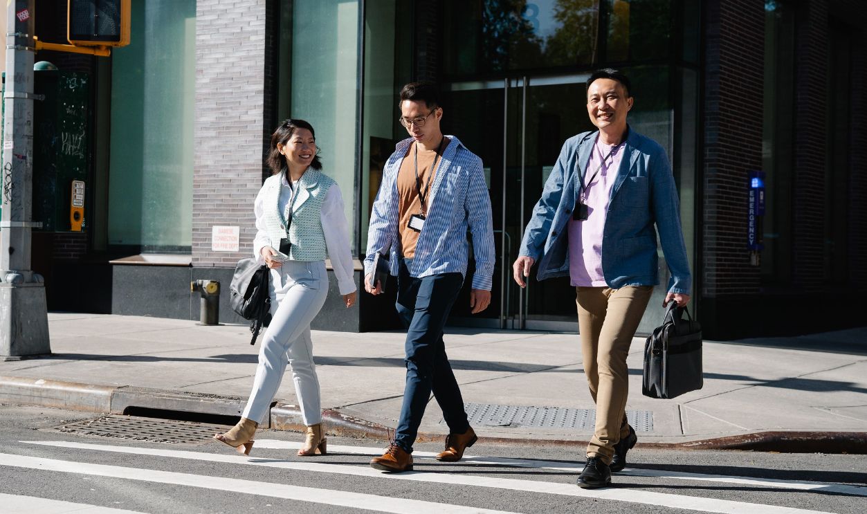 Three business professionals walking across an urban street, smiling and engaged
