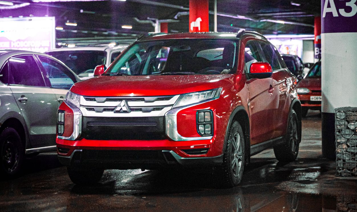 Red SUV parked in an underground garage with reflections on the wet floor