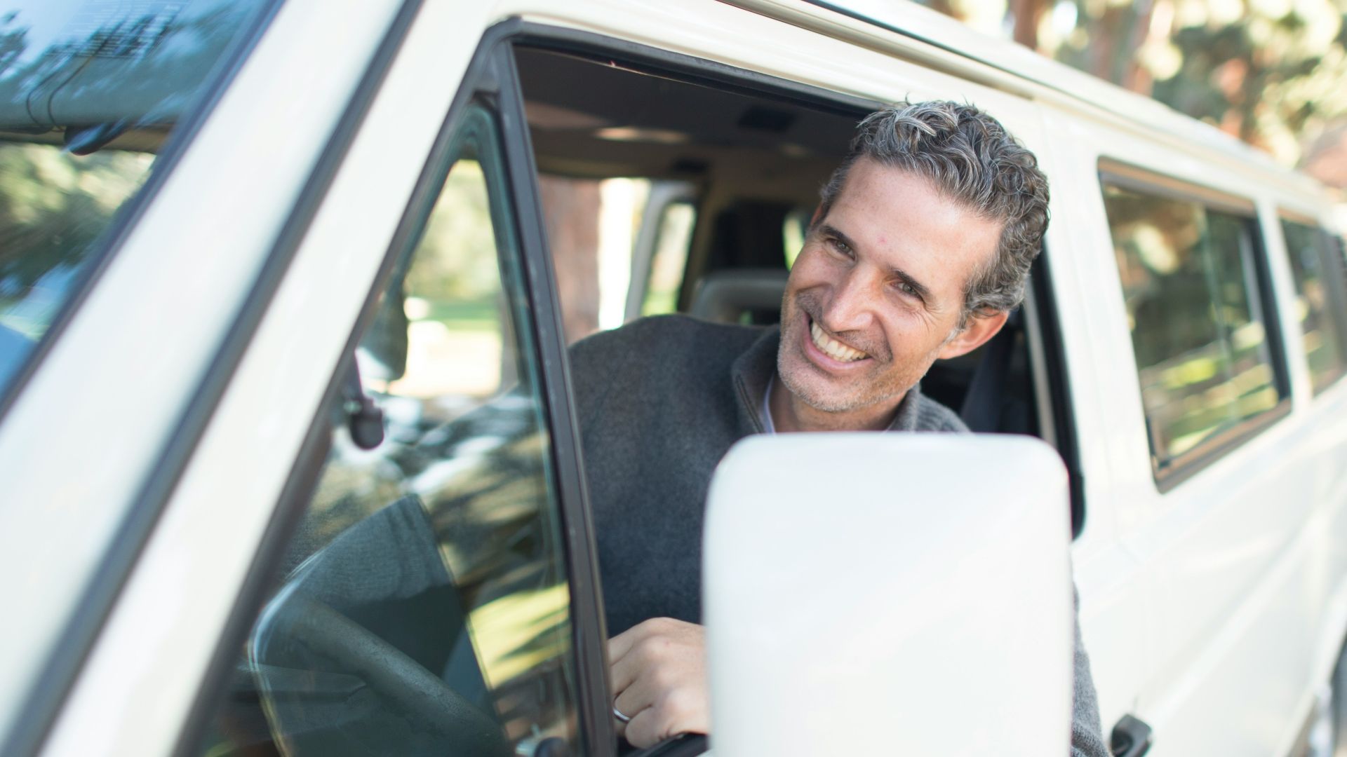 man in gray sweater leaning on van window
