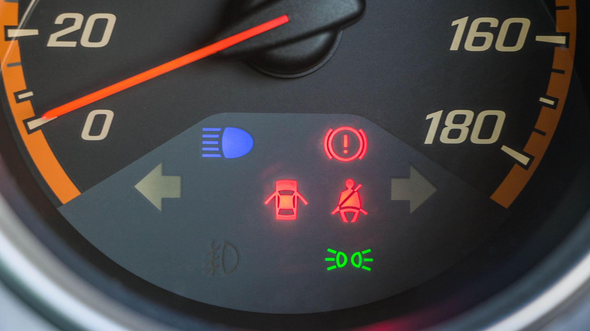 Detailed view of a car speedometer with illuminated warning indicators.