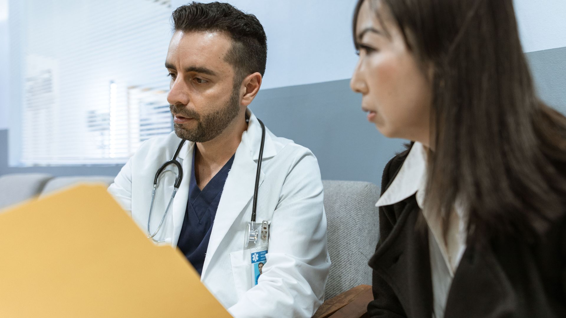 Doctor discusses health records with a patient in a clinical setting.
