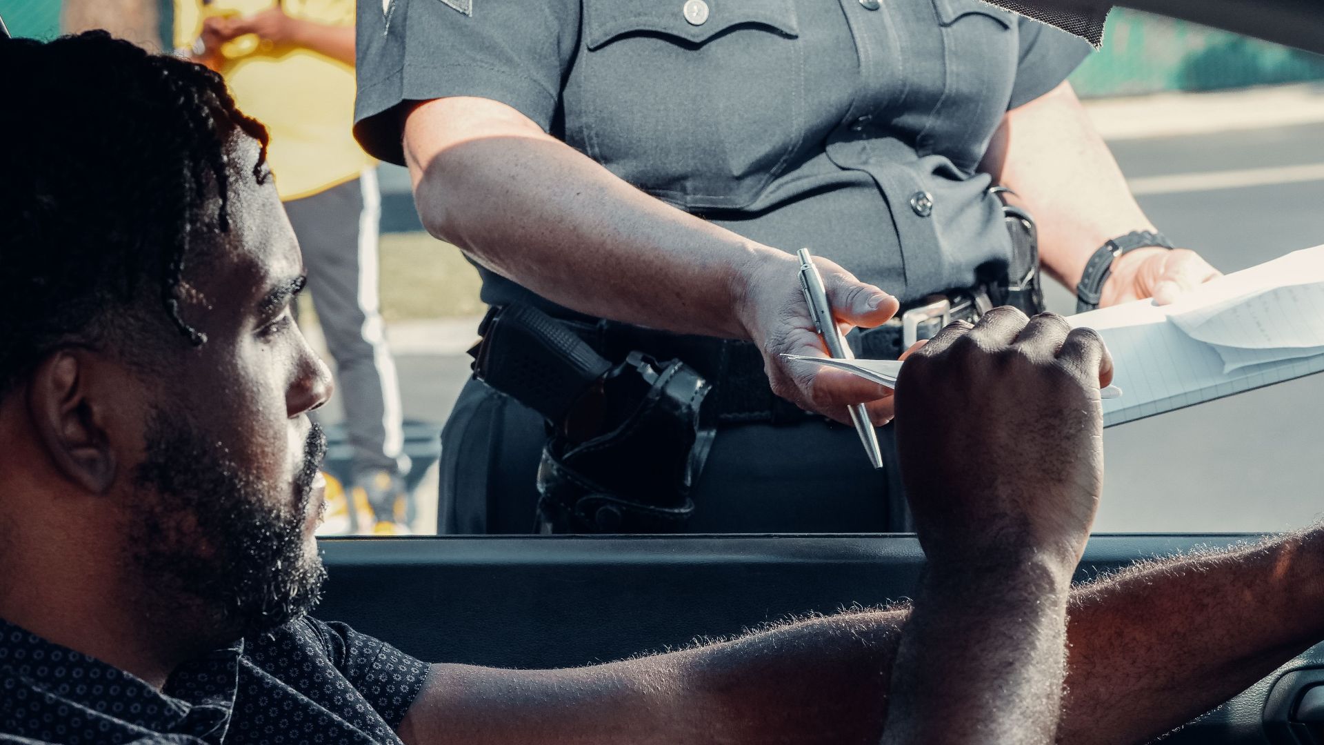 Police officer handing a traffic ticket to a driver during roadside inspection.