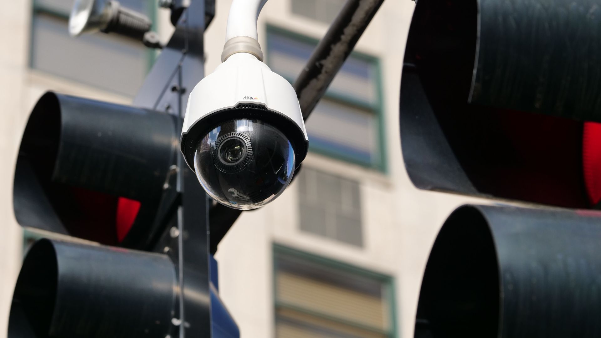 Close-up of a modern dome security camera monitoring an urban street.