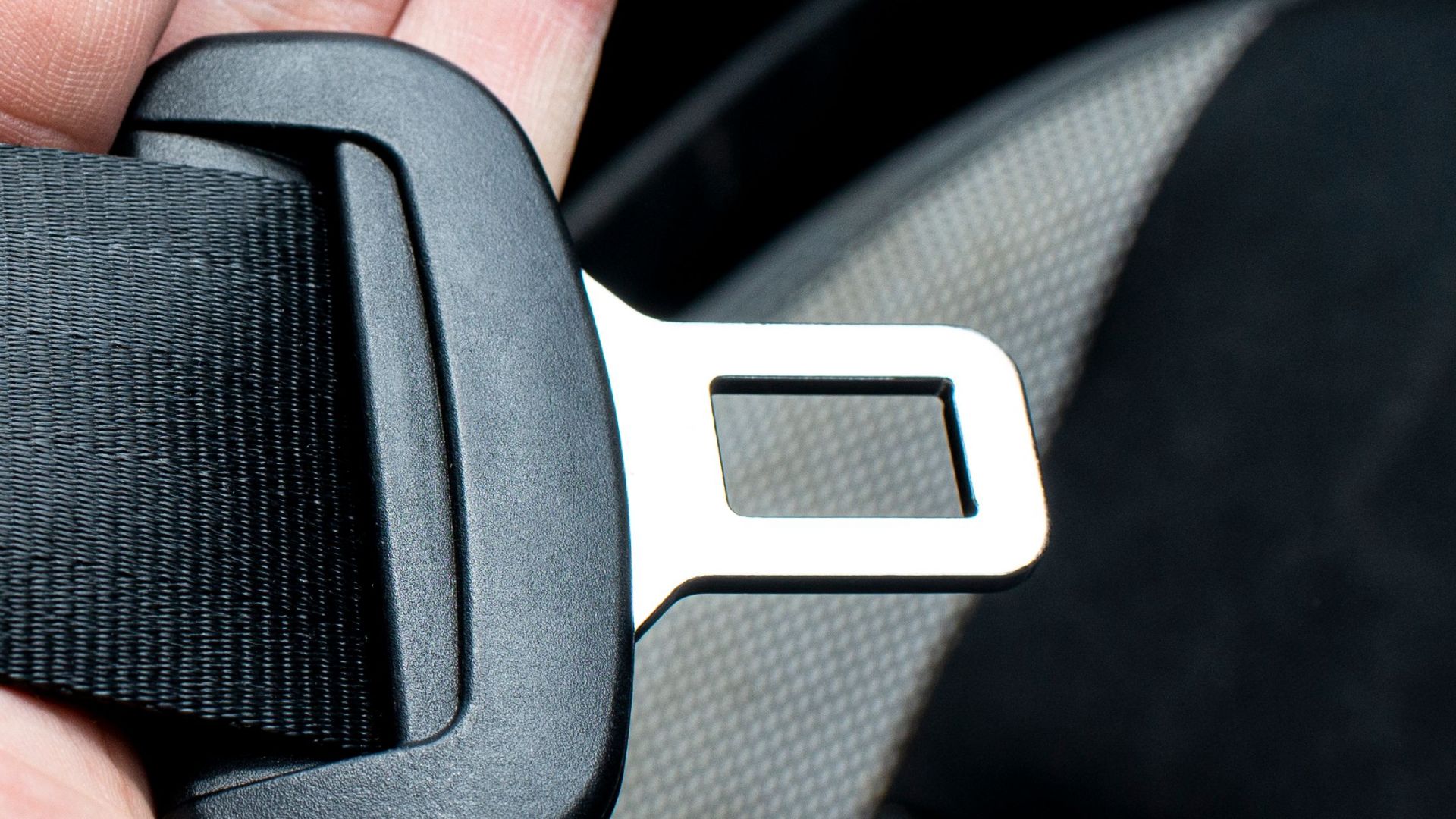 Close-up of a hand holding a car seat belt for safety and security.