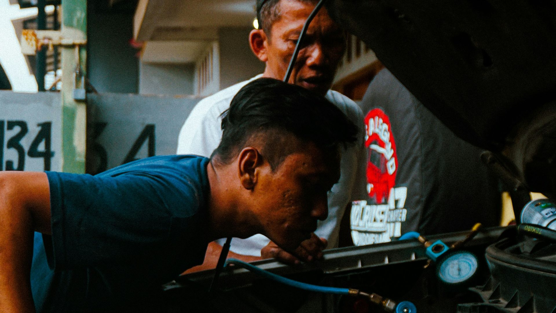 two men working on a car engine in a garage