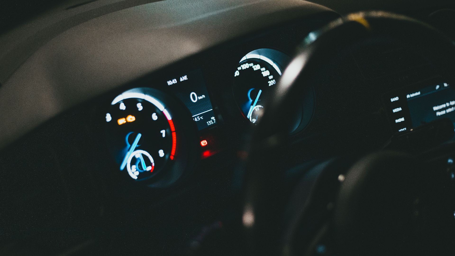 Detailed view of an illuminated car dashboard with speedometer and odometer visible.