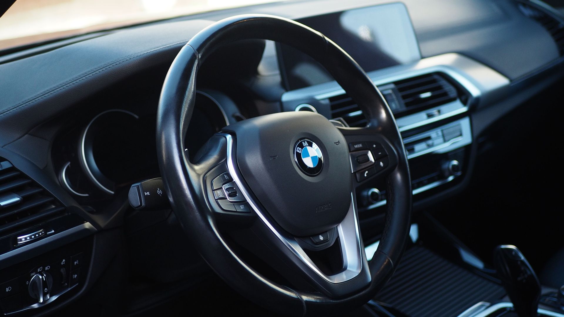 Close-up of a modern BMW car interior, focusing on the sleek dashboard and steering wheel.