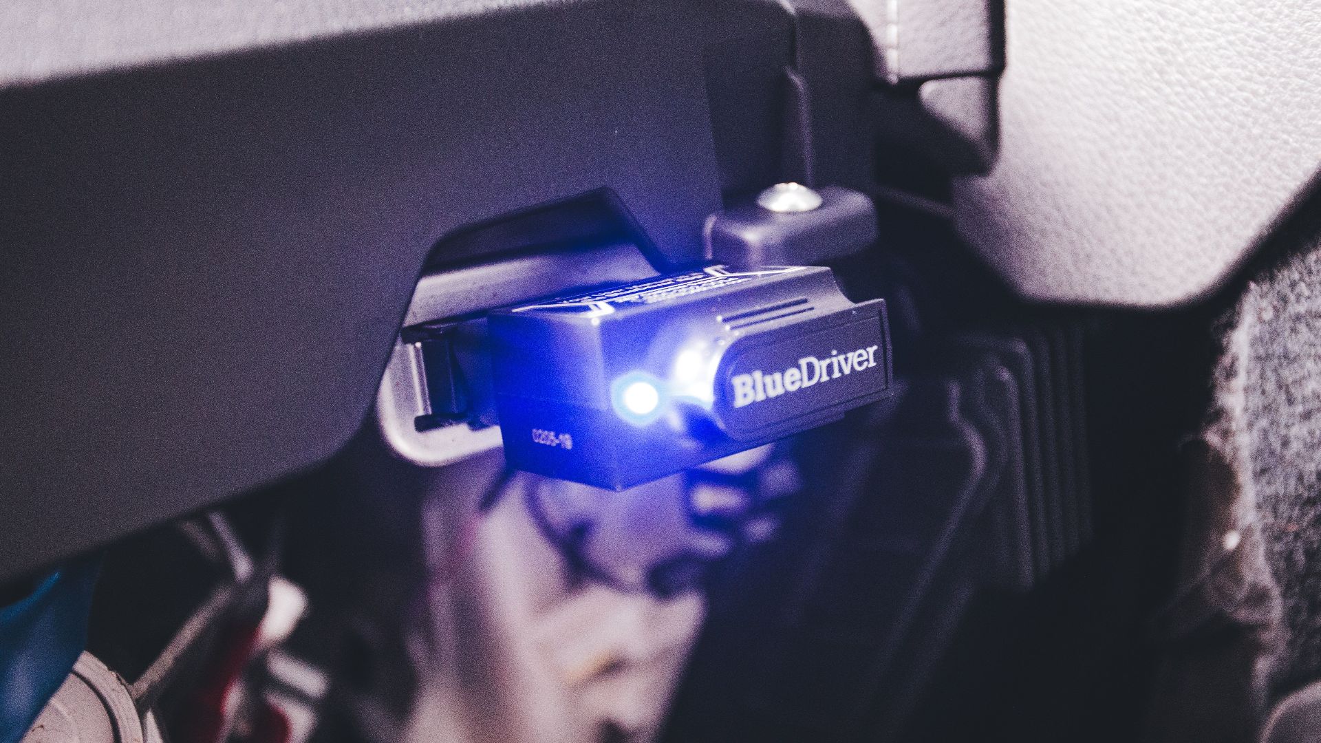Close-up of a BlueDriver electronic car diagnostic tool plugged in a vehicle.