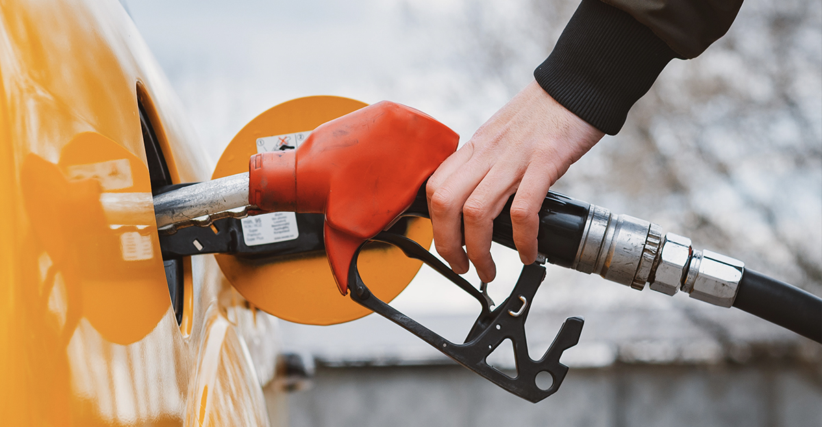 Hand holding a gas pump, filling his car's tank.