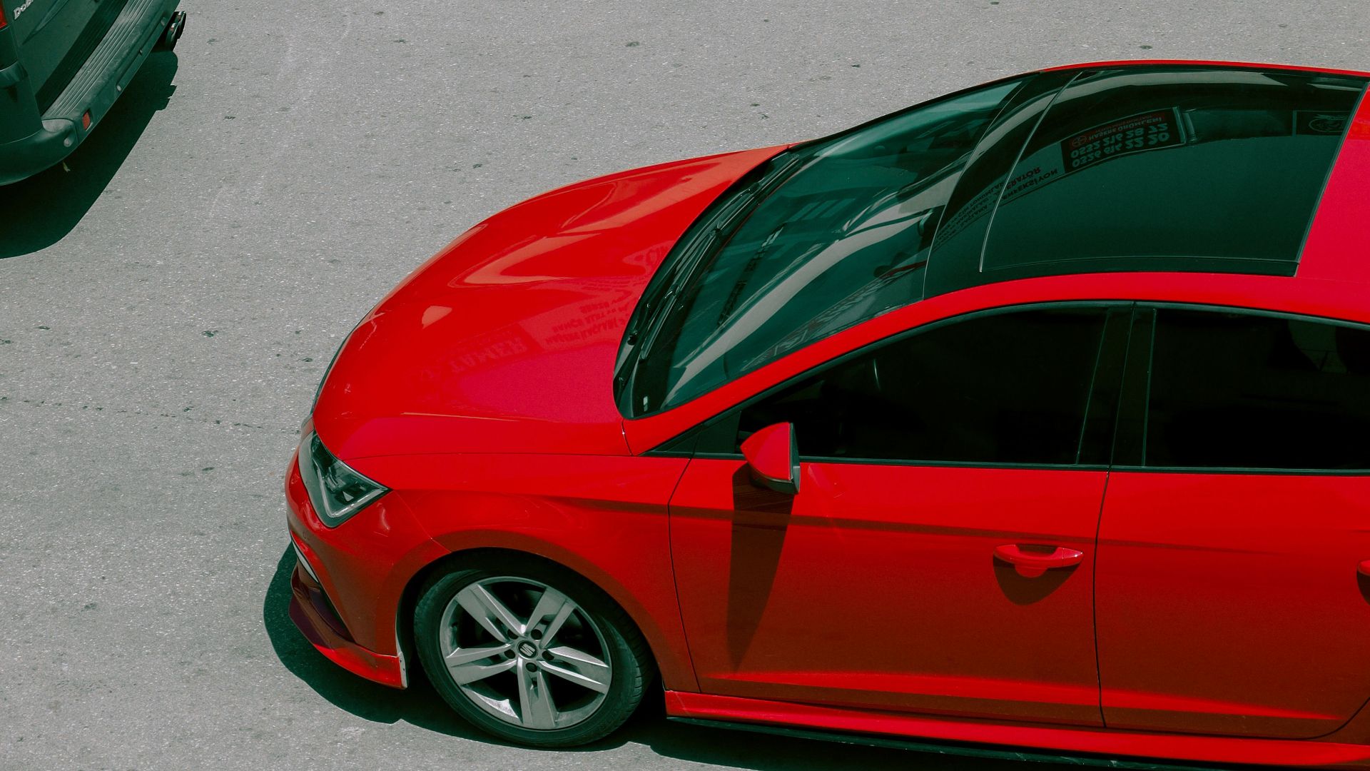 A vibrant red car captured from above on a city street, showcasing modern urban life.