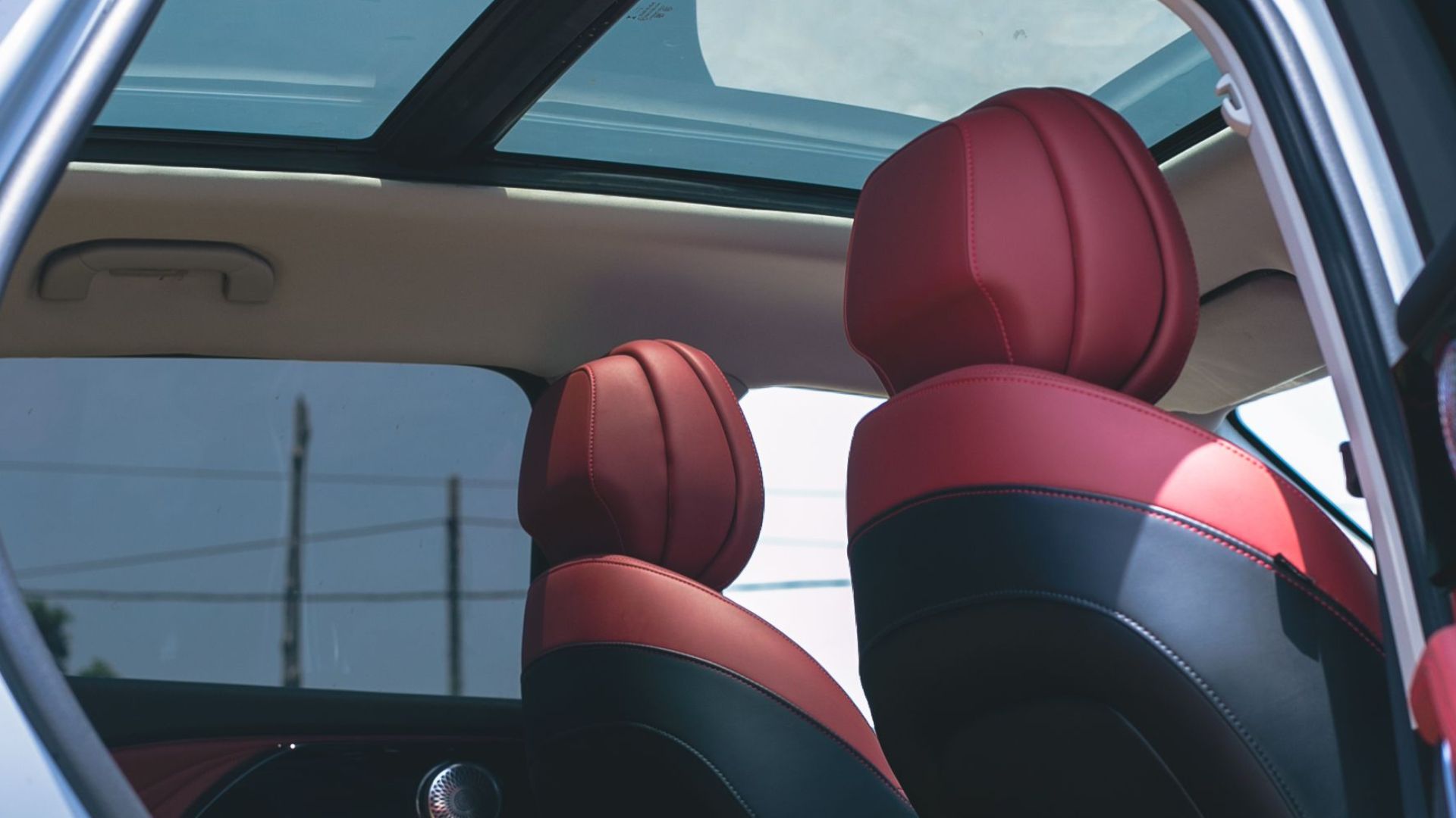 Modern car interior featuring sleek red leather seats and panoramic sunroof.