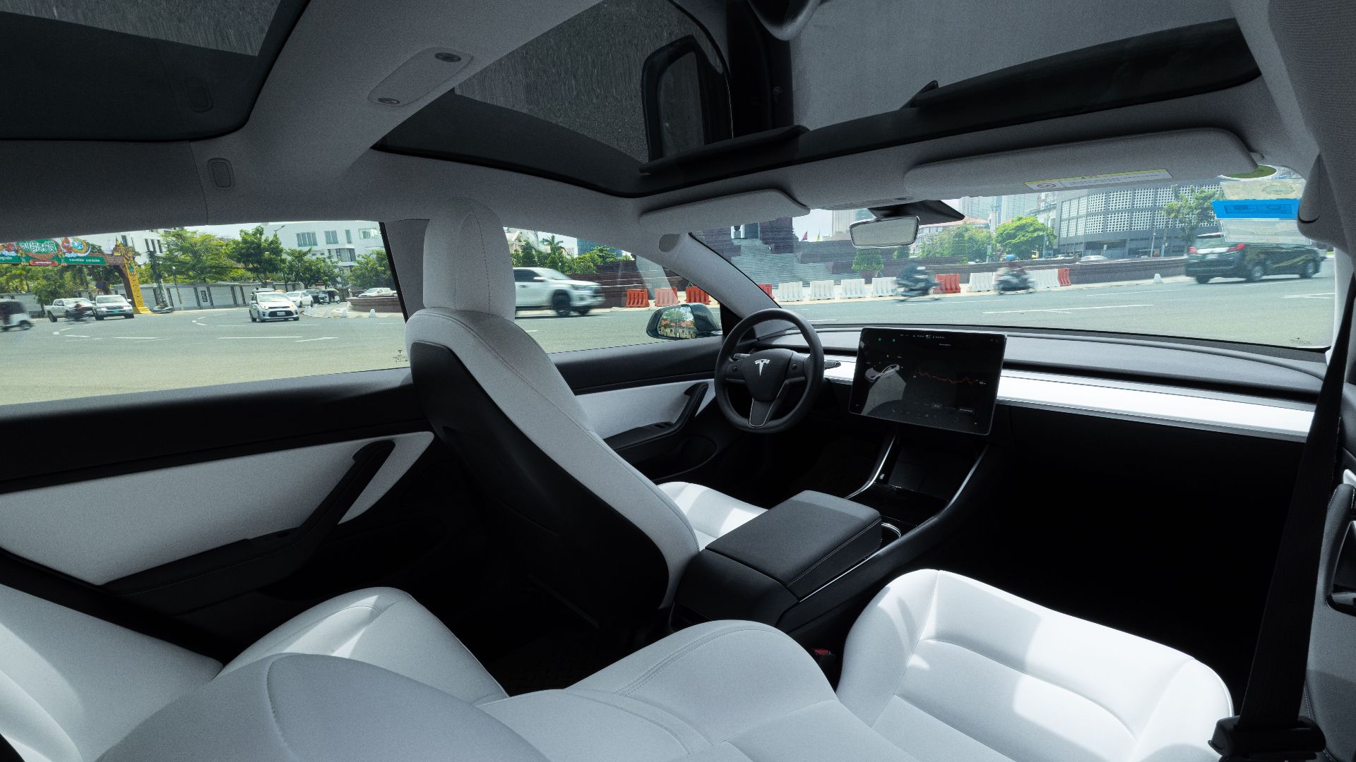 Elegant interior of an electric car featuring luxurious white leather seats and a panoramic view.