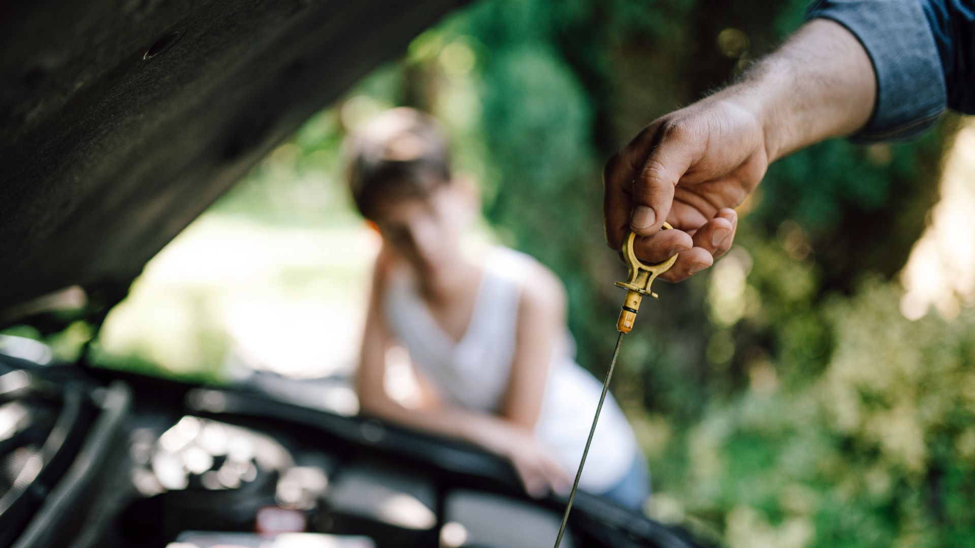 Car maintenance activity in a garden setting with a child observing the oil dipstick check