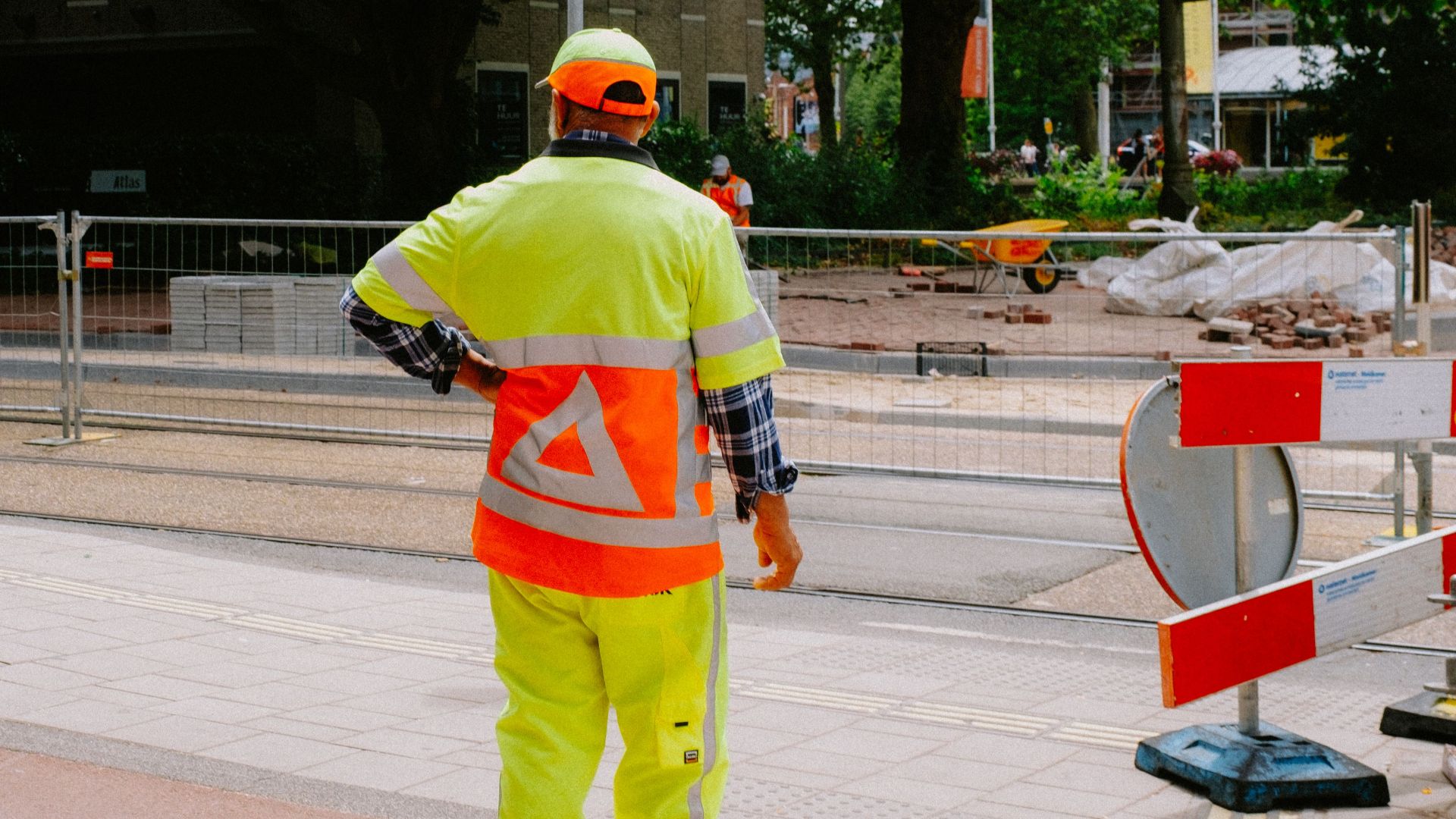 Construction worker in safety gear managing roadside site operations.