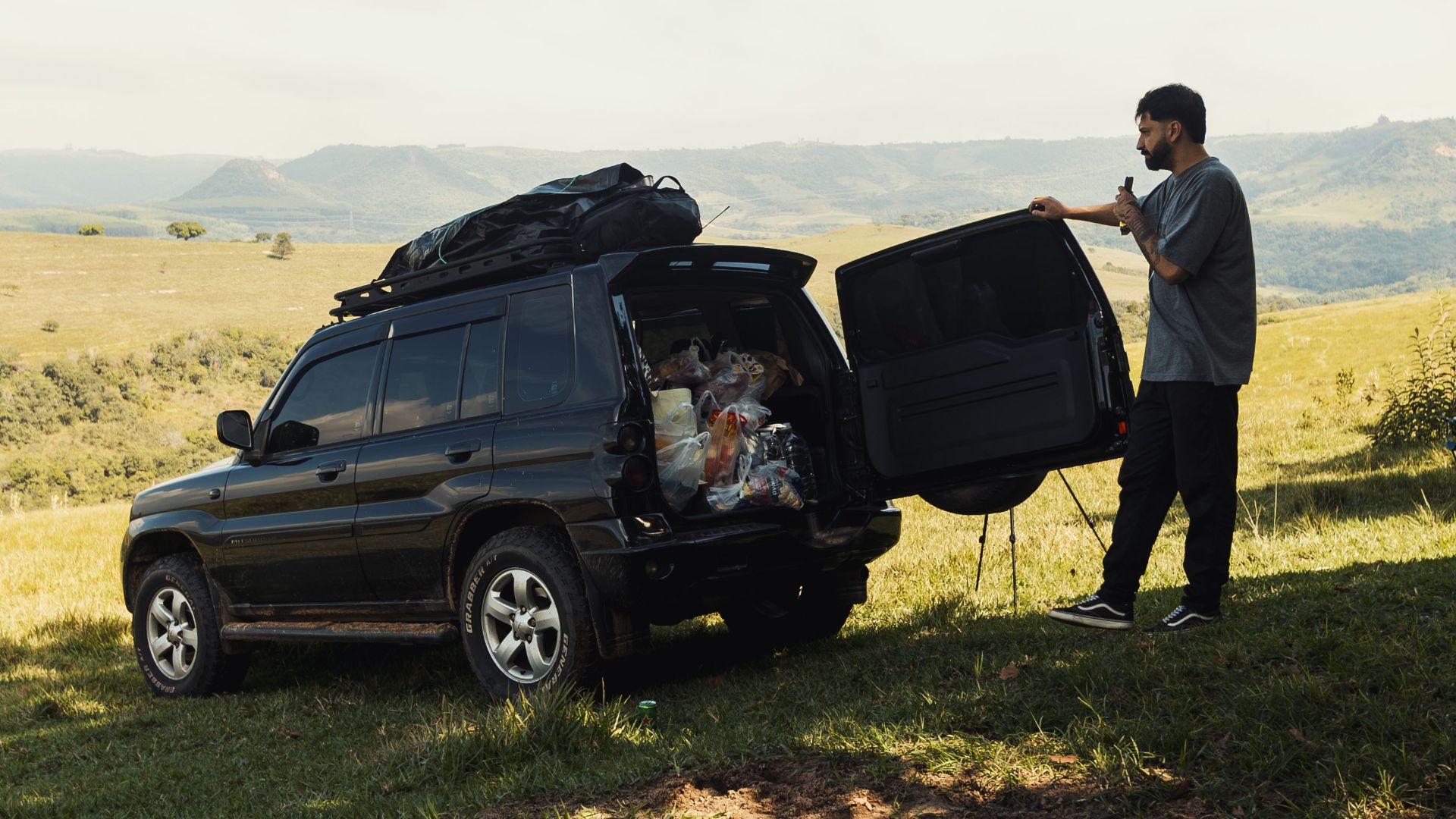 Man with SUV packed for adventure in a scenic outdoor setting, ready to explore.