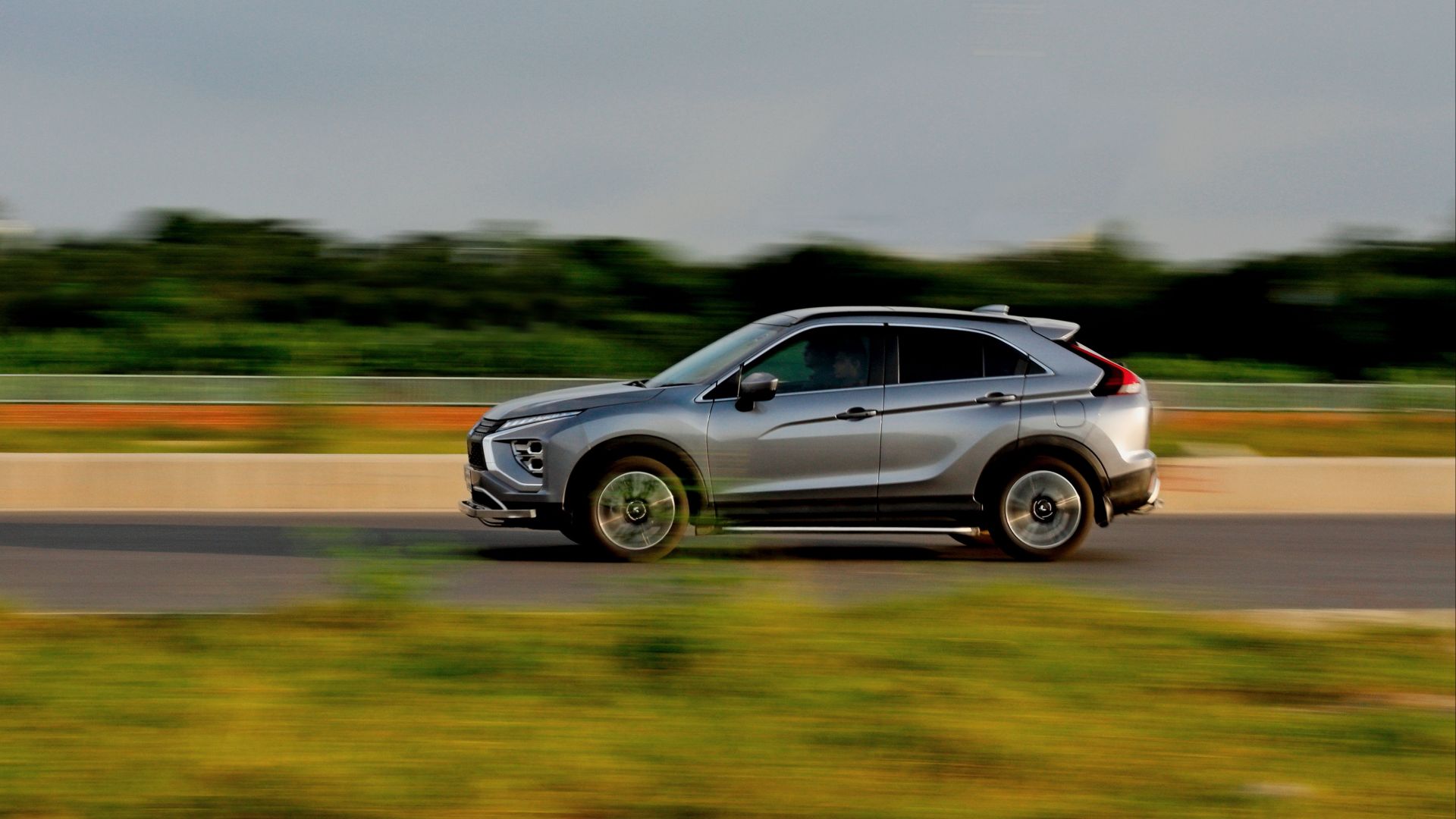 A sleek silver car in motion captured on a highway in Dhaka, Bangladesh.