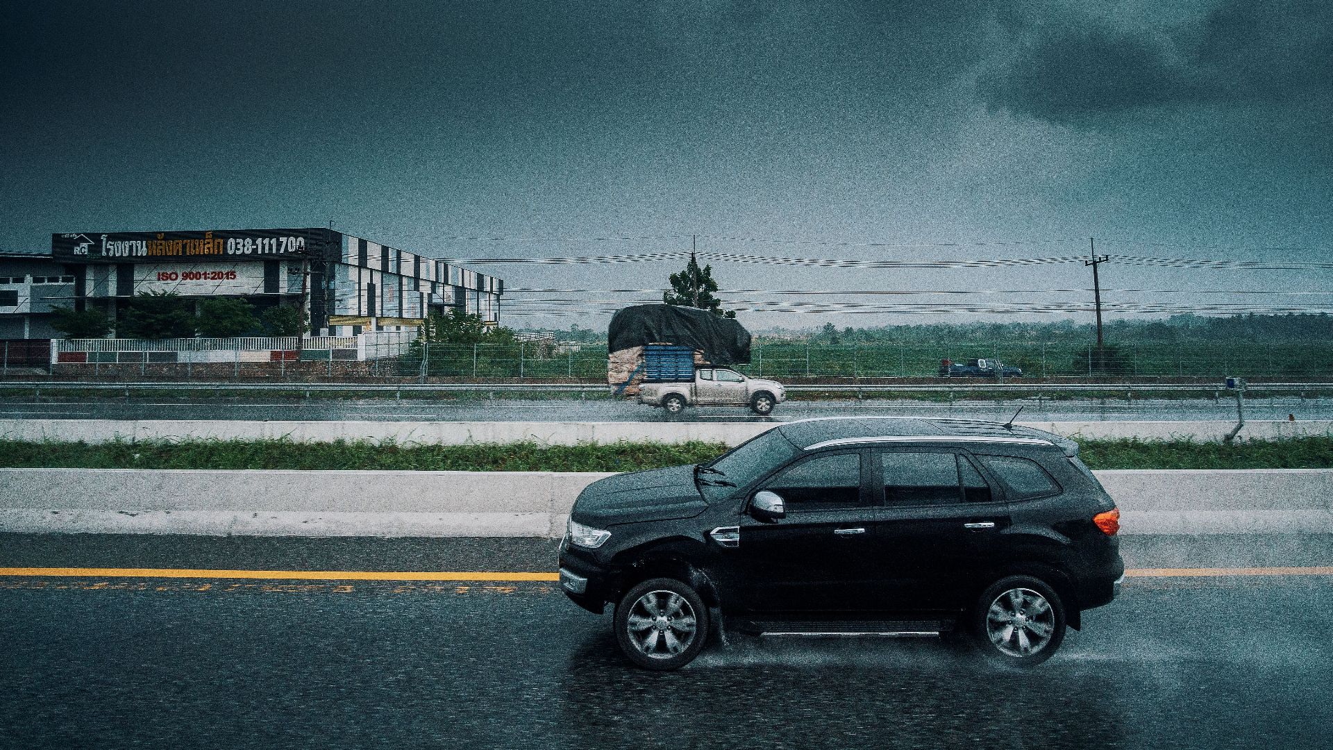 Black SUV travels on a rainy highway, showcasing stormy weather and transportation dynamics.