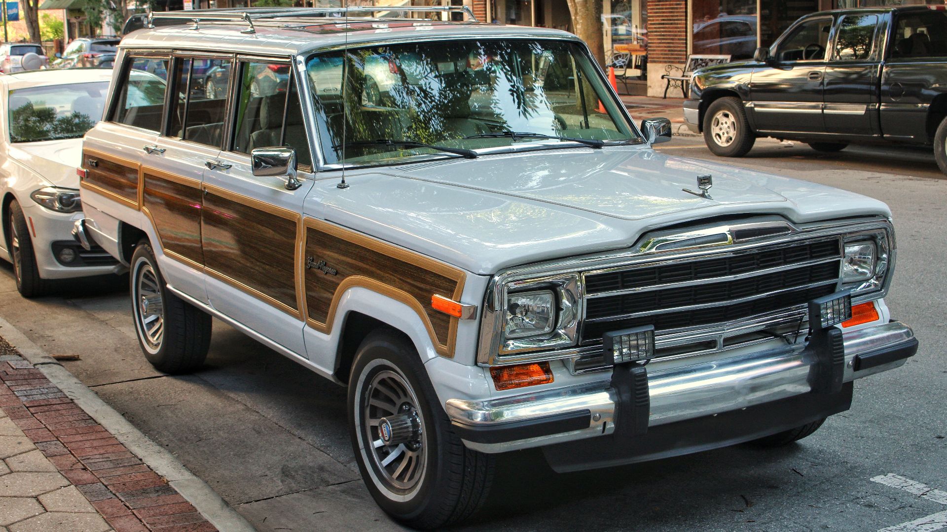 Classic Jeep Wagoneer with wood paneling parked on an urban street, reflecting a vintage aesthetic.