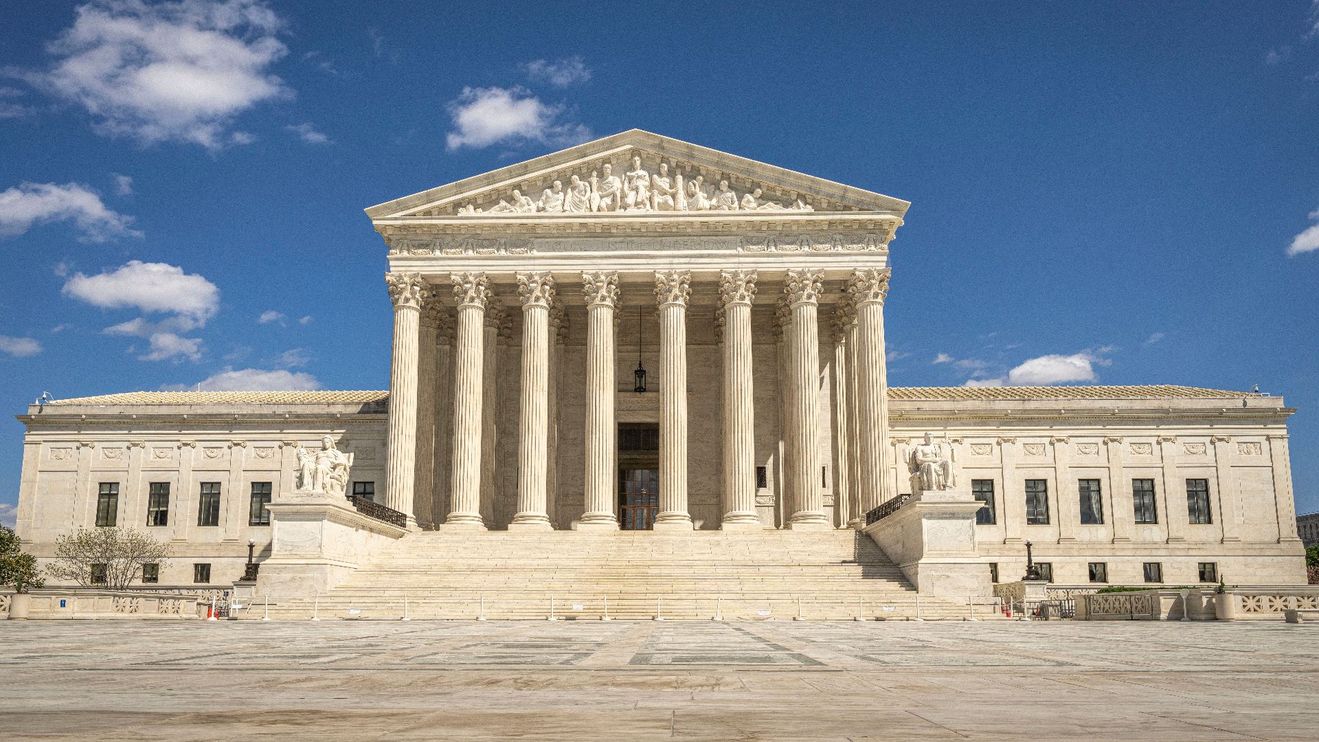 The majestic facade of the United States Supreme Court under a clear blue sky.