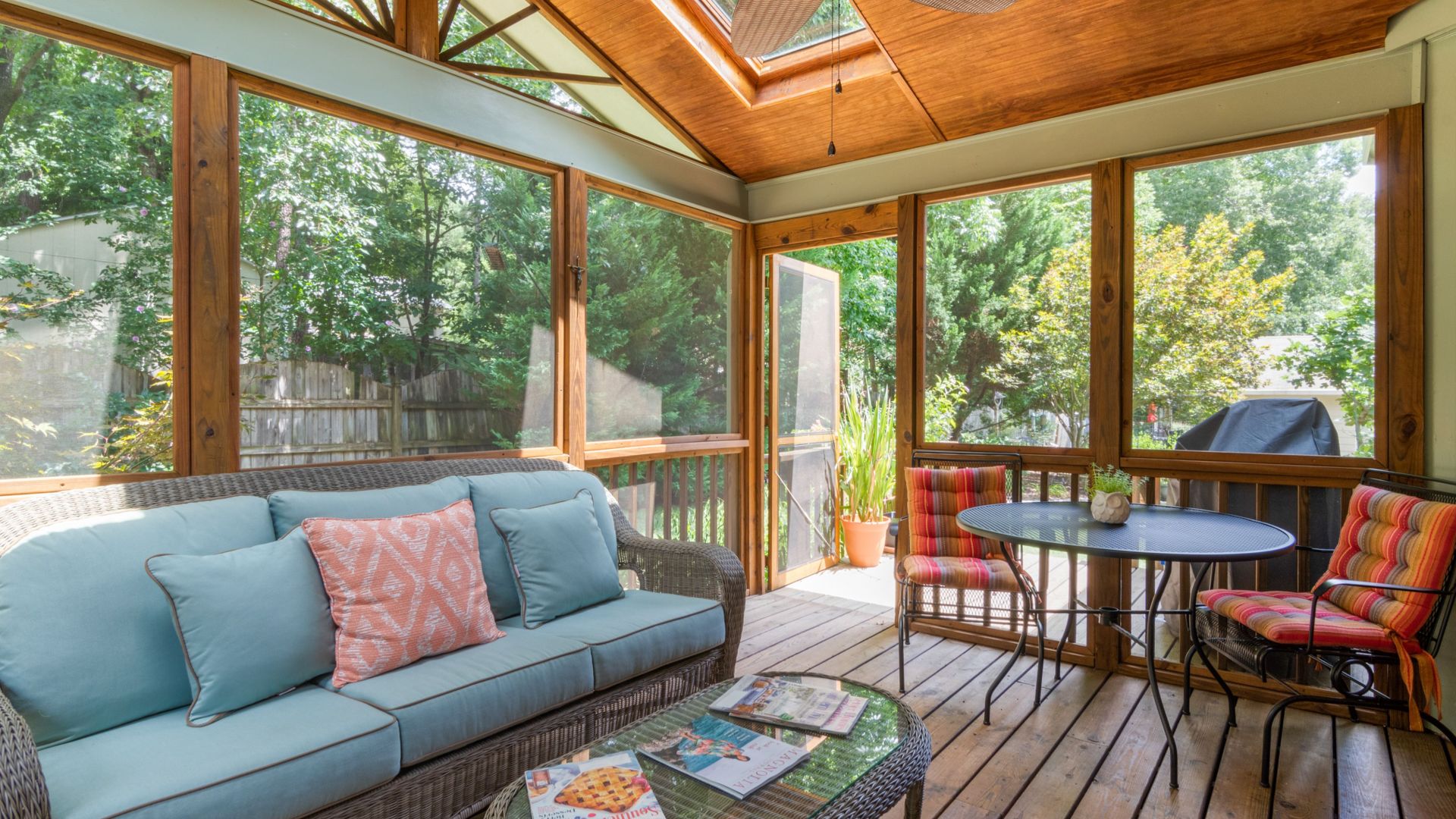 Inviting indoor porch with skylight, wicker sofa, and vibrant decor, perfect for relaxation.