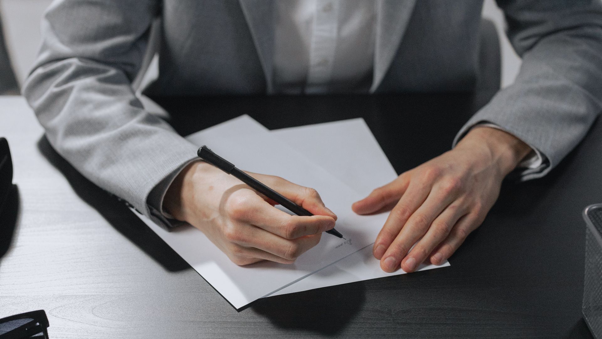Professional hands signing a document in an office setting for business purposes.