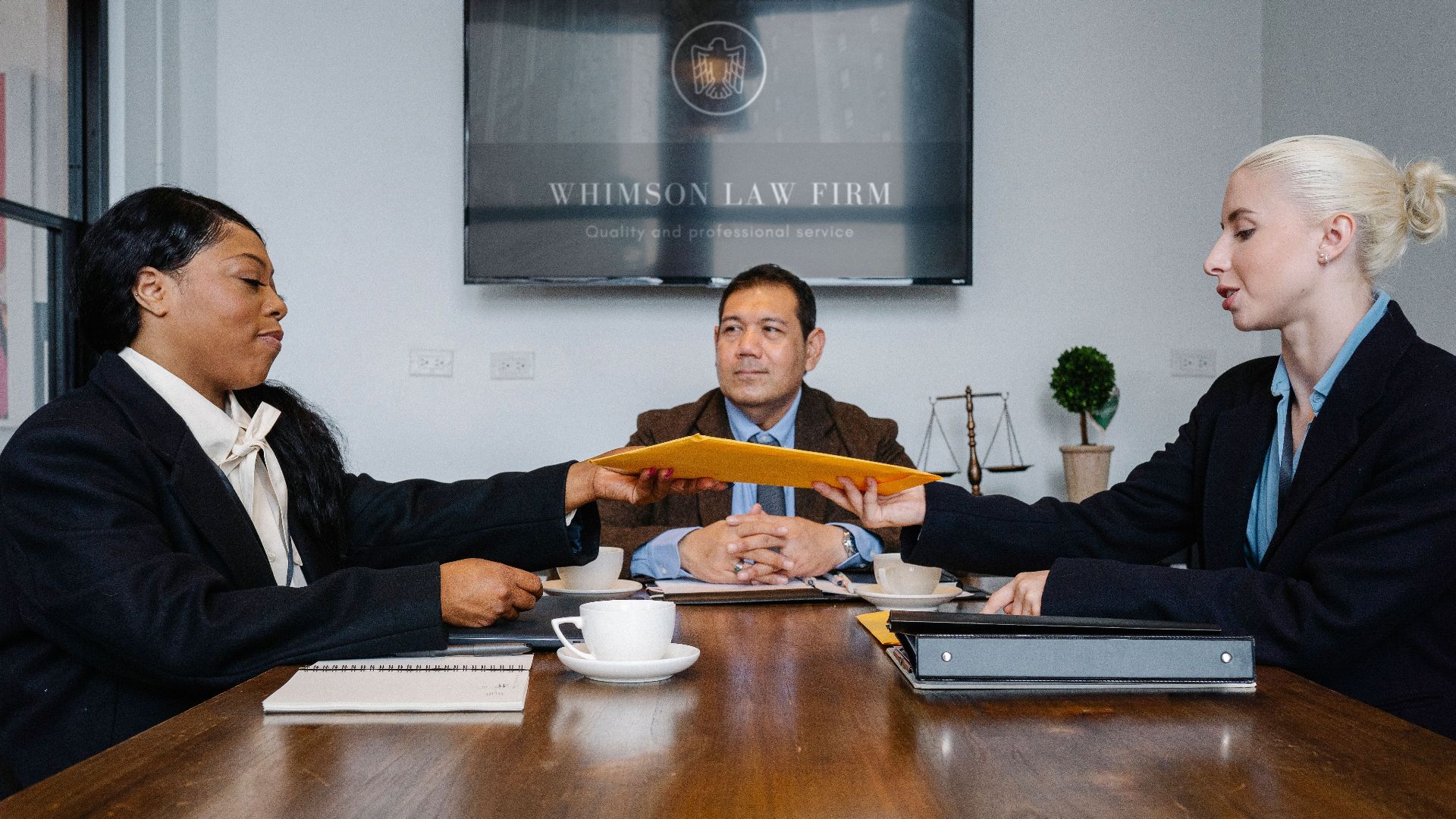 Group of cheerful diverse colleagues discussing court decision at table with notepad and cup