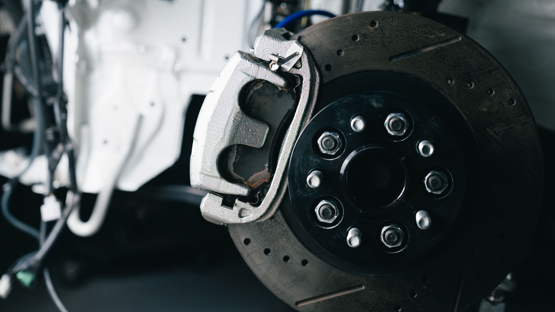 Detailed view of a car's brake caliper and disc in a workshop setting.