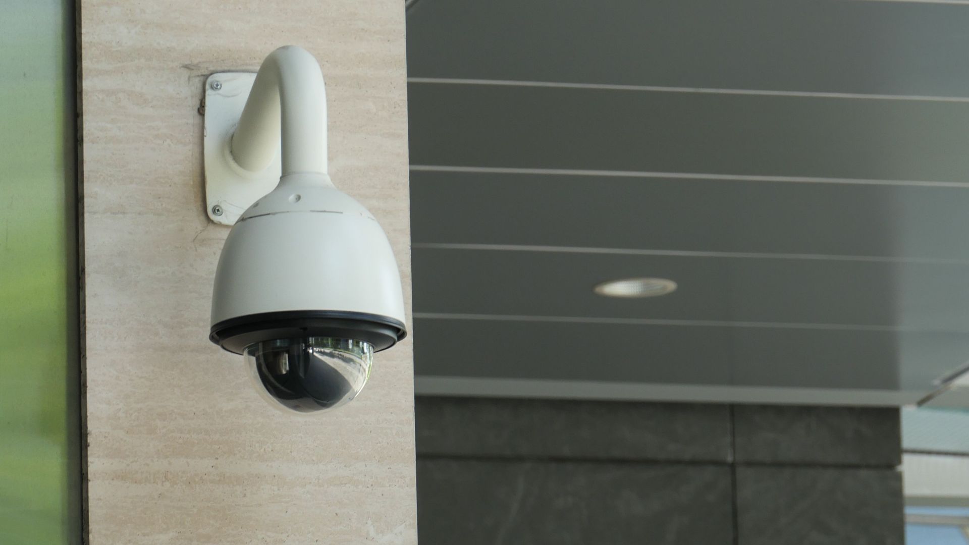 Close-up of a mounted security camera on a modern building's exterior.