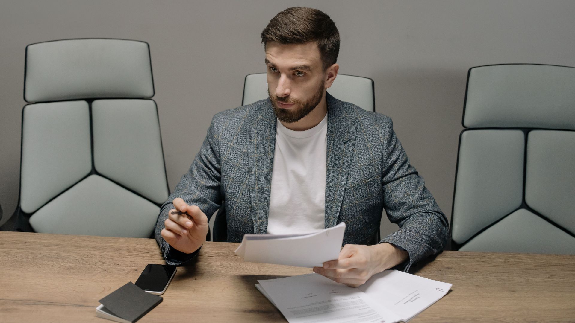 Professional businessman in a suit holding documents during a meeting in an office setting.