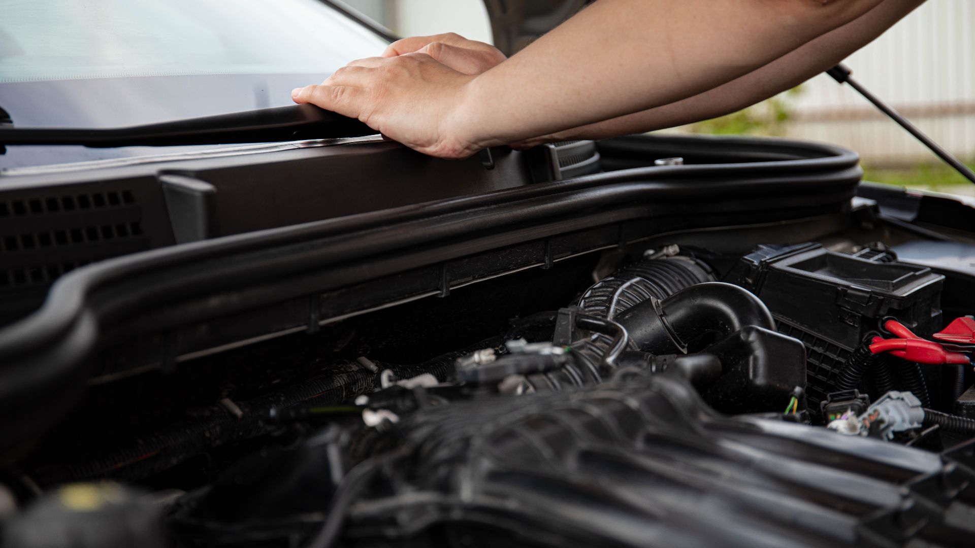 Close-up of hands working on car engine. Detailed view of automotive repair.