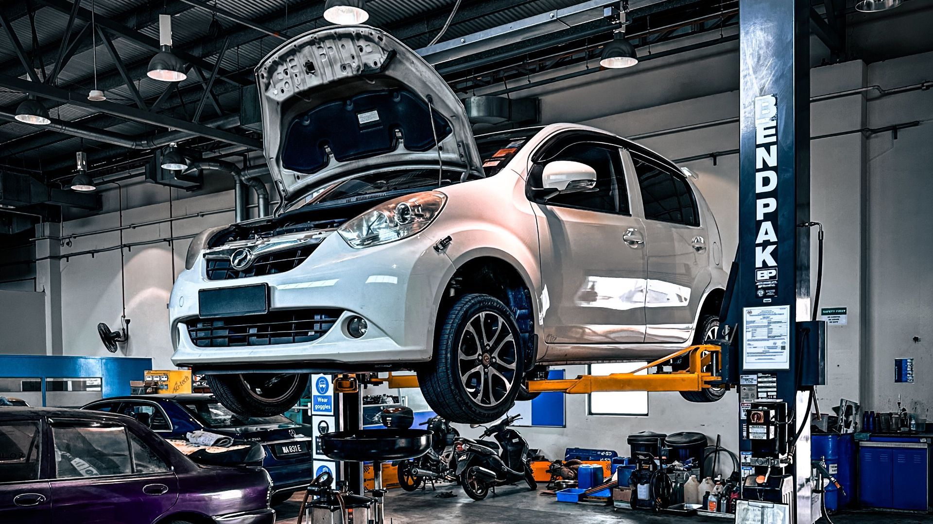 A car is lifted on a hydraulic lift in a well-equipped auto repair shop.