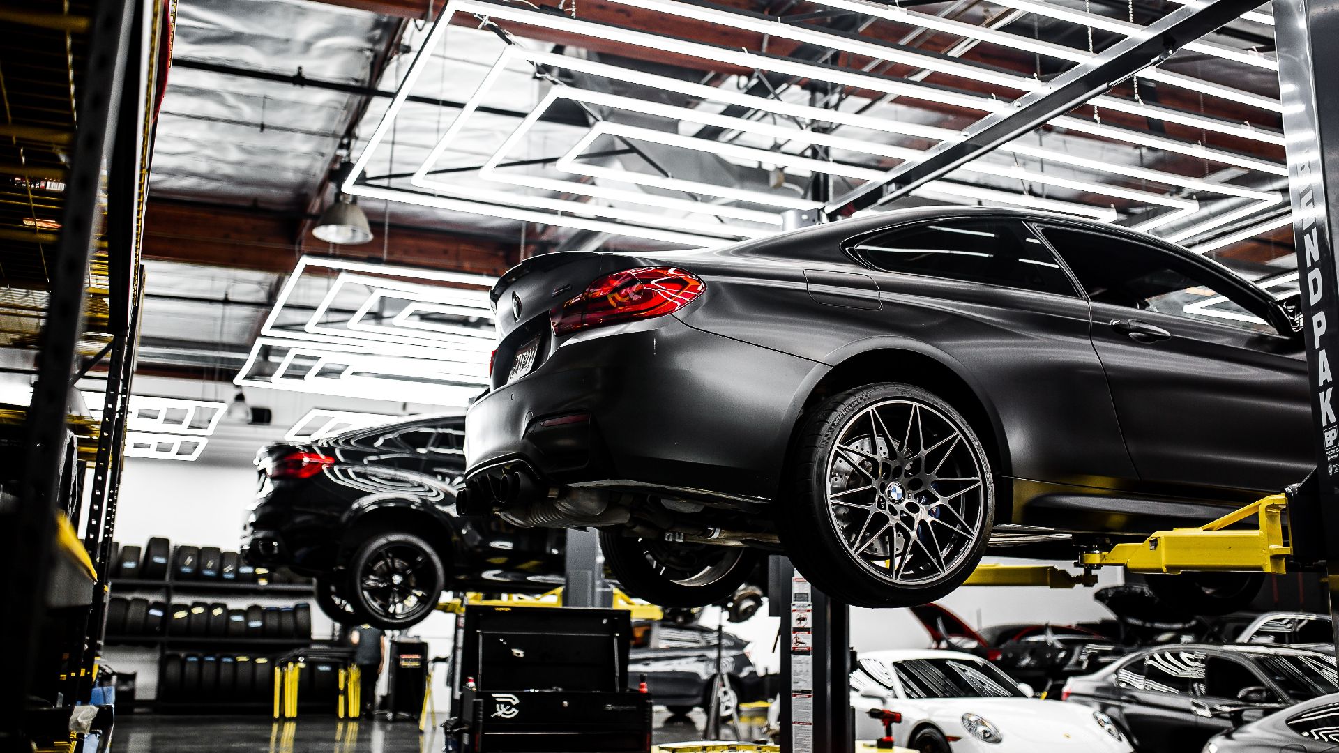 A modern car repair shop showcasing vehicles on lifts and a well-lit, organized interior.