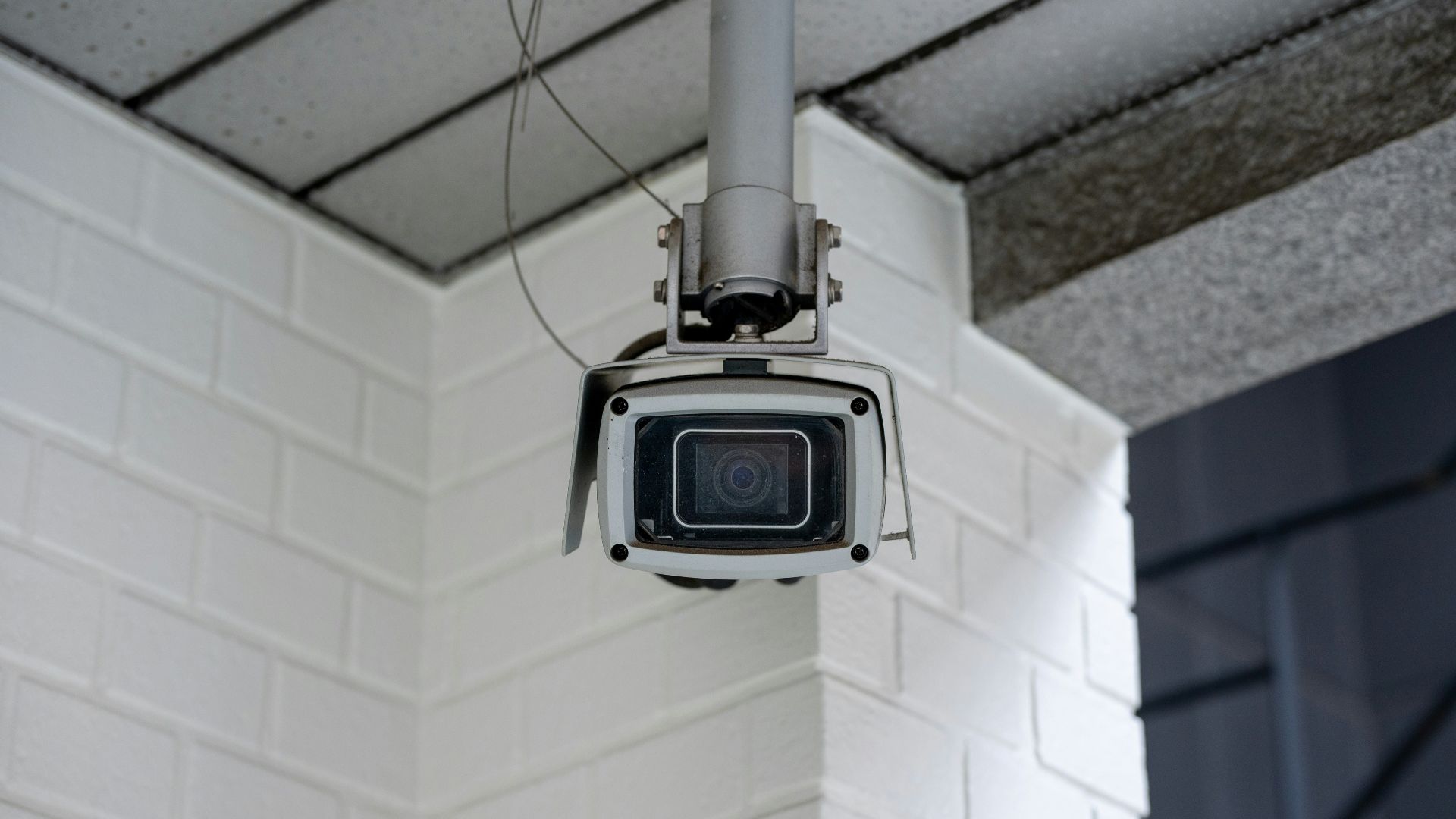 Security camera mounted on a white brick wall.