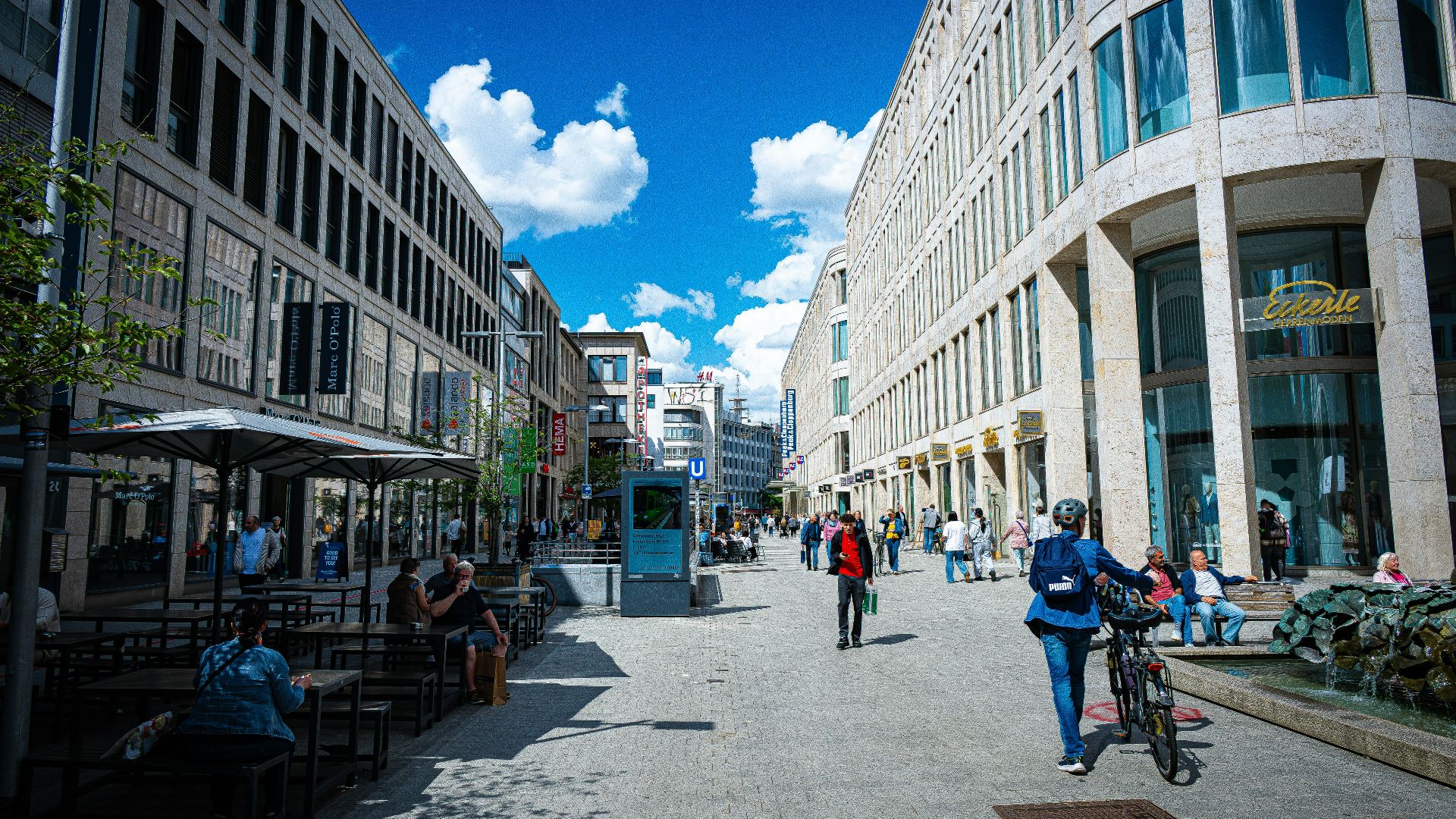 A bustling pedestrian street with modern buildings and people.