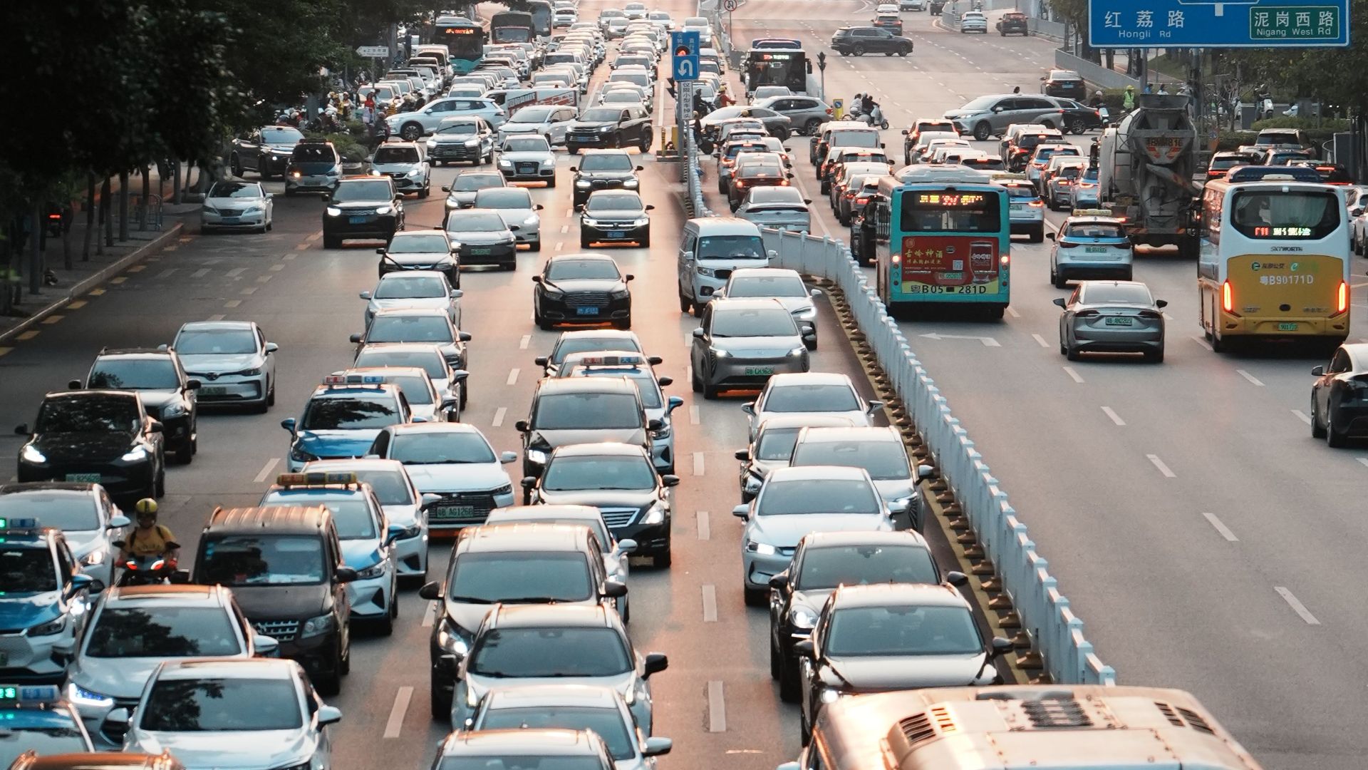 Dense urban traffic flows during sunset in a bustling cityscape with high-rise buildings and vibrant life.