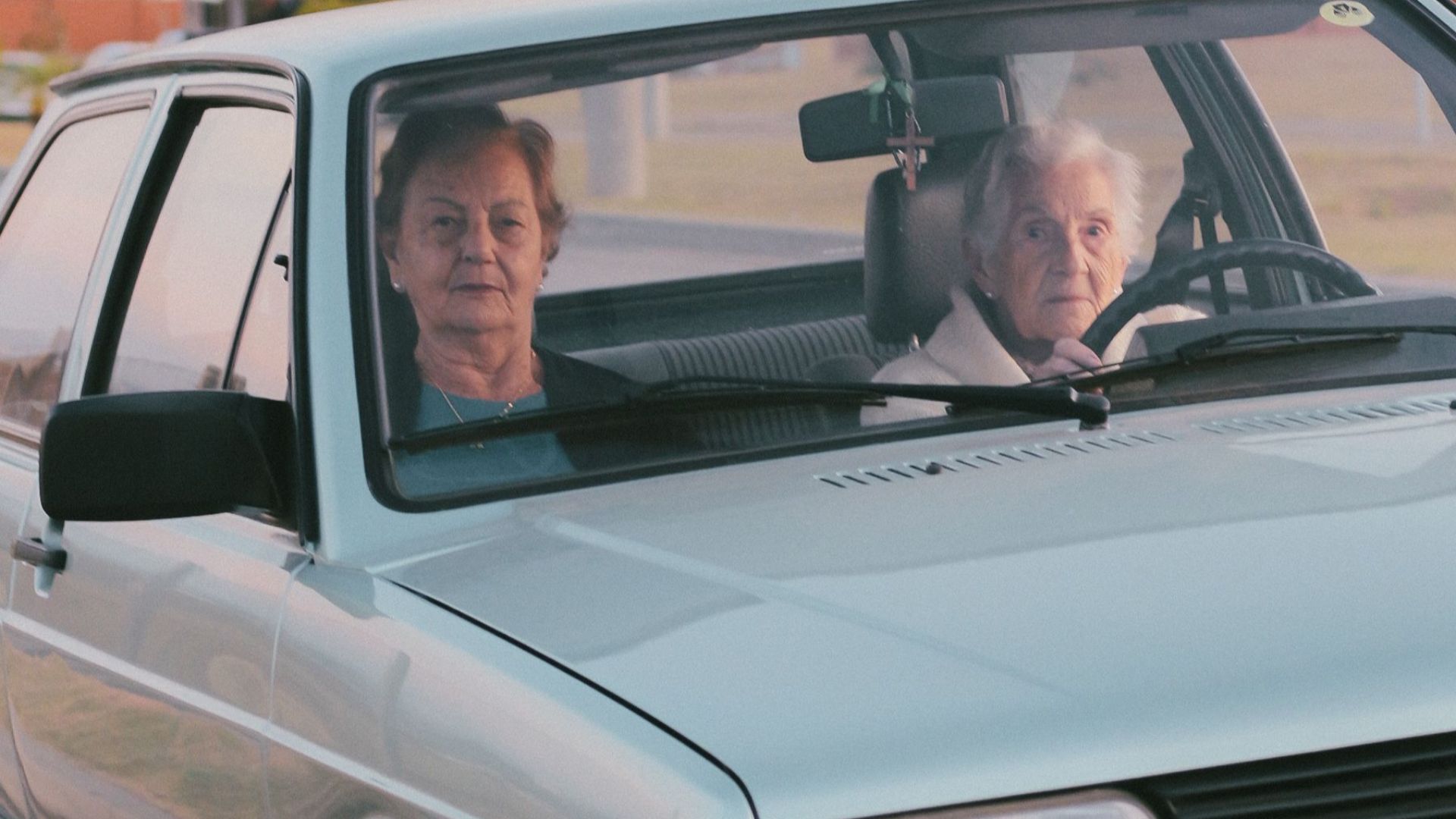 Two senior adults in a car driving through a city at twilight, showcasing urban exploration.
