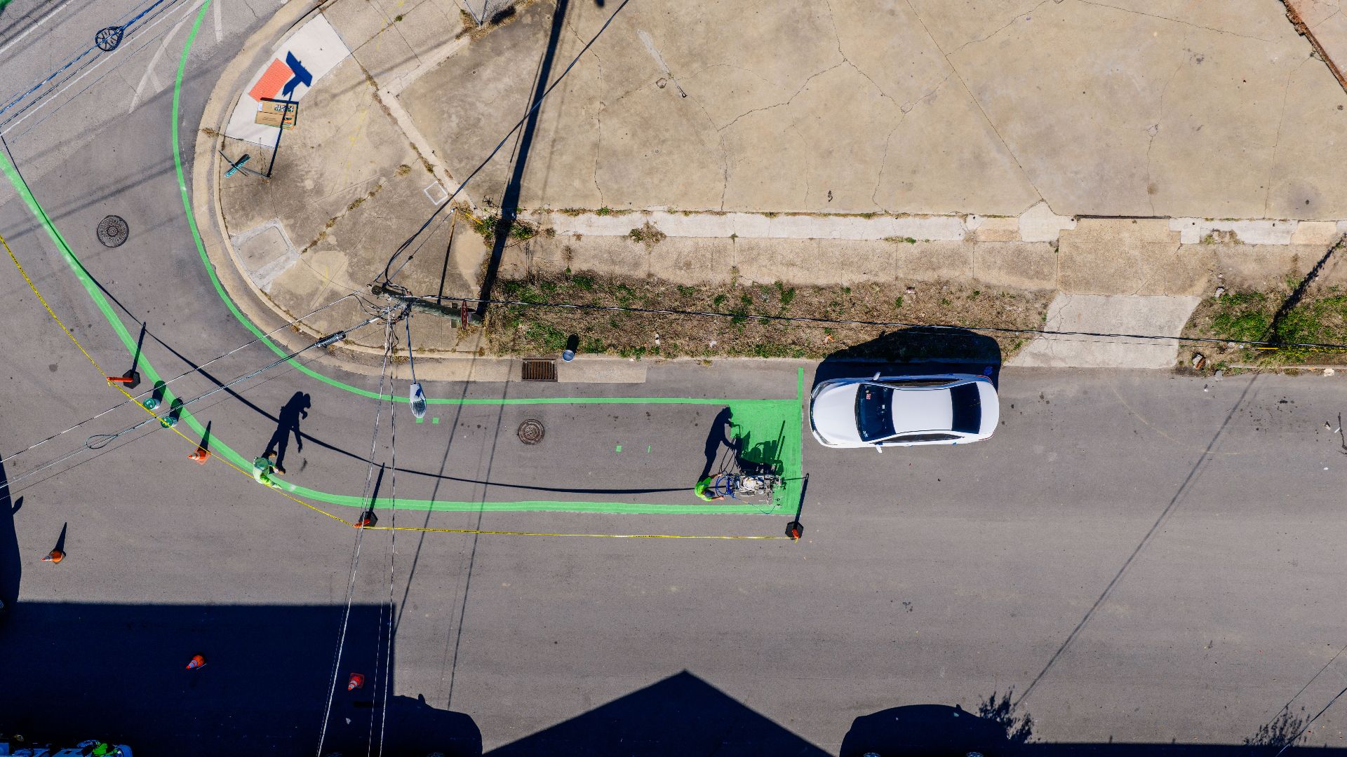 Aerial shot of a car and green bike lane markings on urban street.