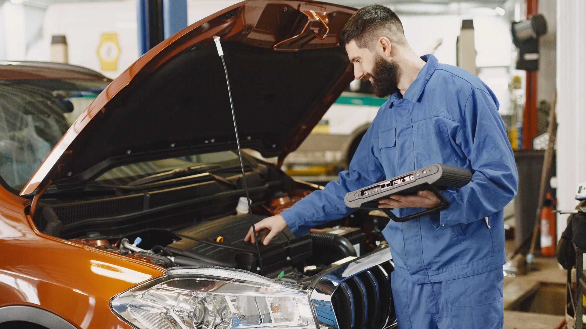 Skilled mechanic working on car engine diagnostics in a modern garage.