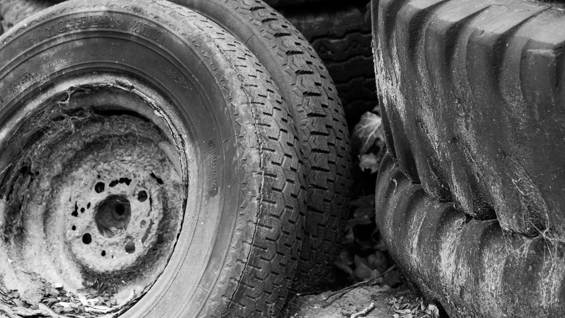 Black and white photo of old, discarded tires in an outdoor setting.