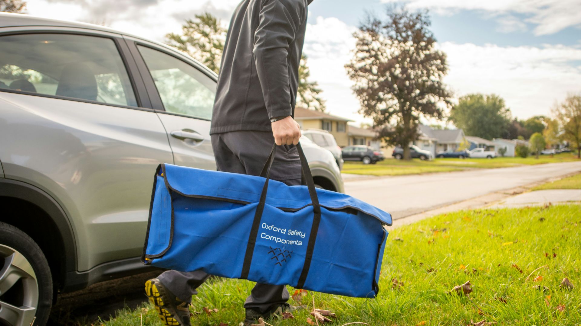 a man carrying a large blue bag next to a car