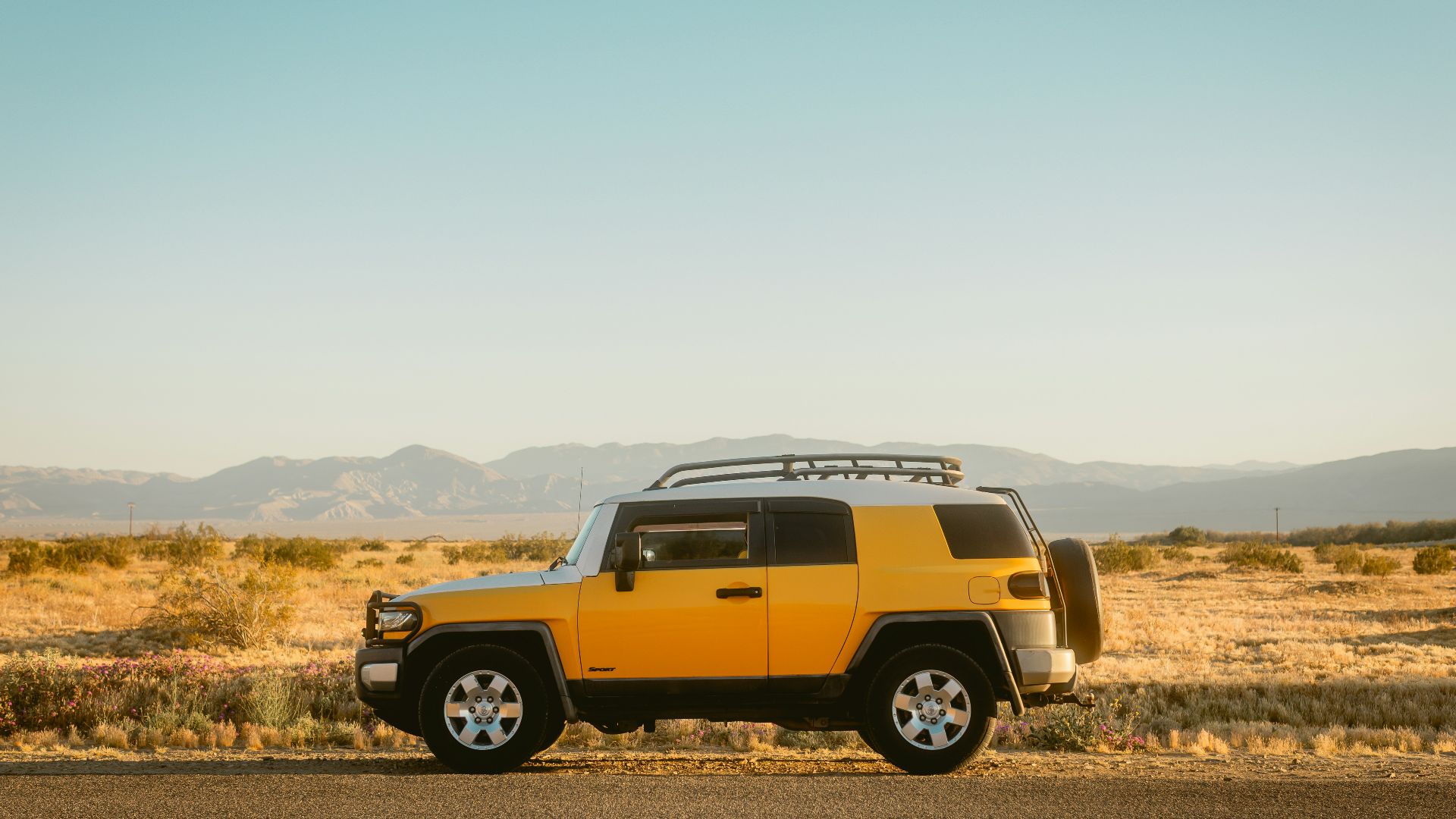 Yellow suv parked on a desert road